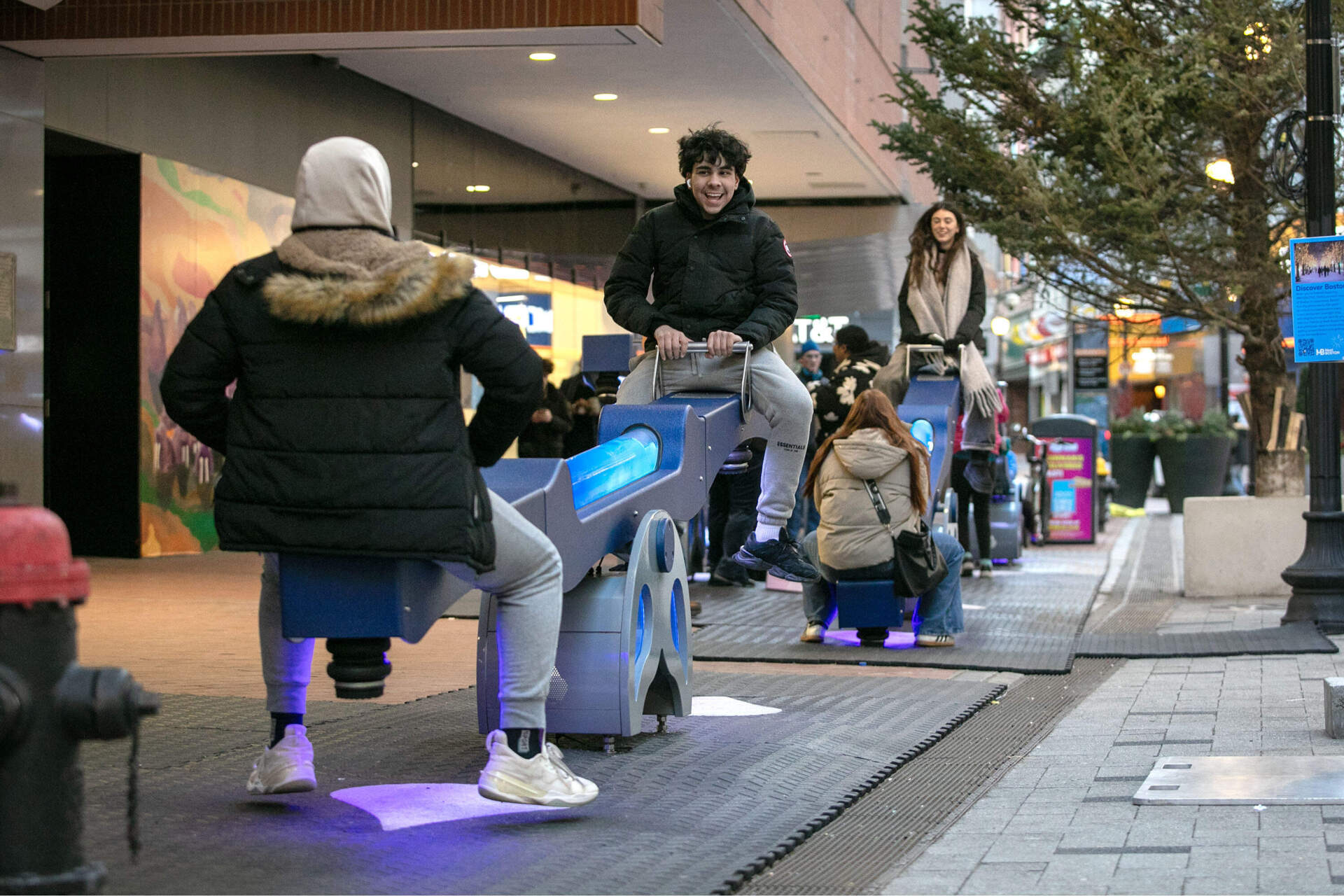 People passing along Summer Street stop to play on the "e/motion" see-saws by Olivier Landreville, one of the installations in downtown Boston's walkable art experience, Winteractive. (Robin Lubbock/WBUR)
