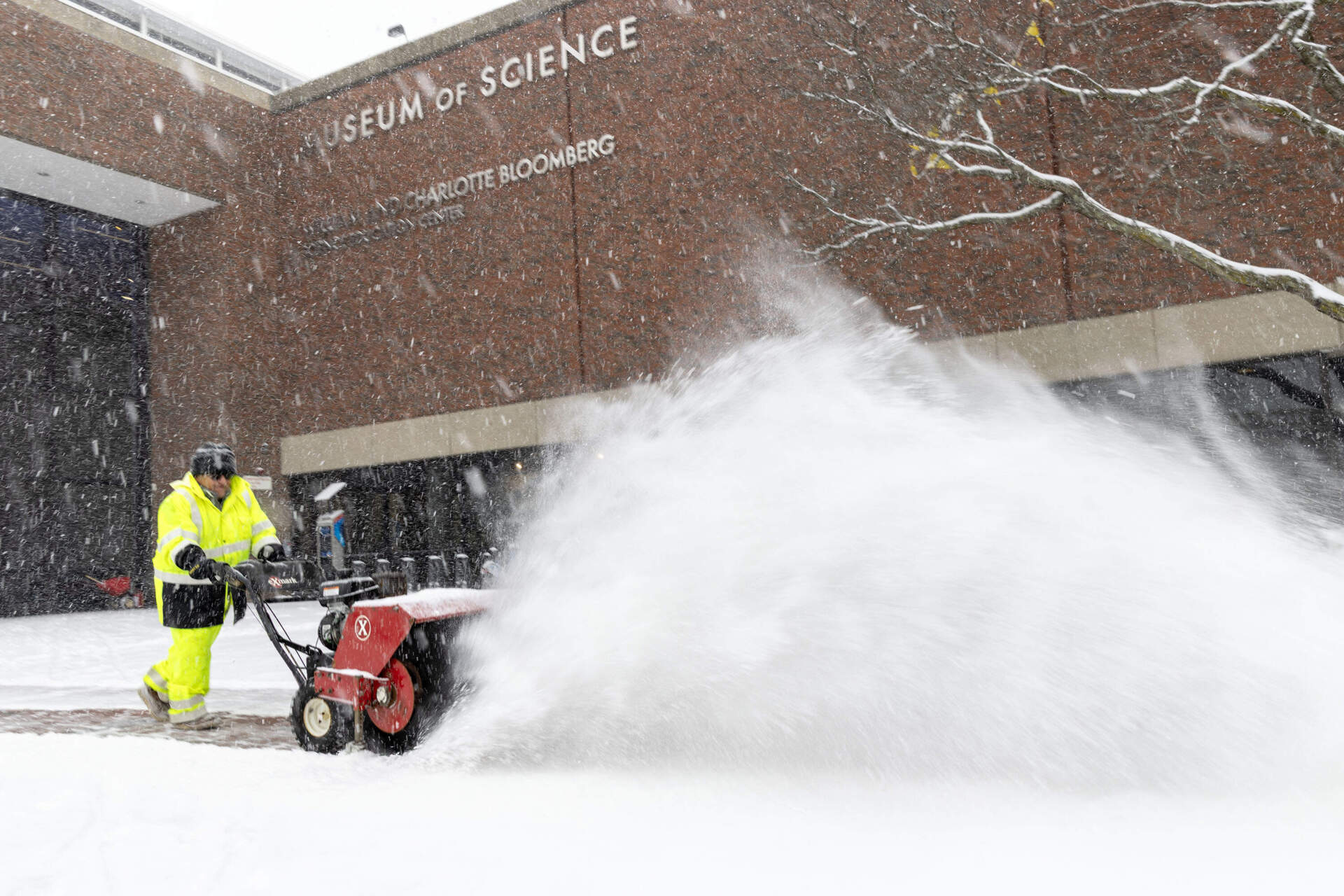 A workman clears snow from the entrance to the Museum of Science on Sunday, Jan. 25, 2026. (Robin Lubbock/WBUR)