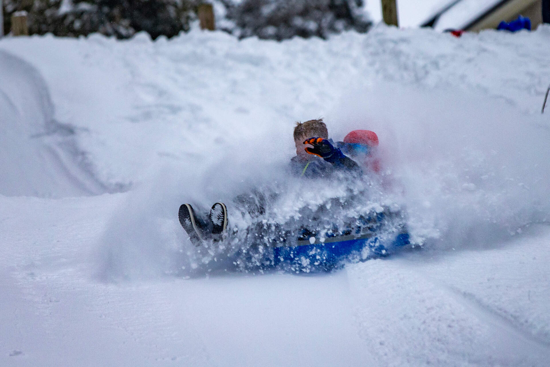Snow flies into the faces of Will Barry and Rhys Manthripragada as they ride a snow tube down Nawshawtuc Hill in Concord the morning after the first major snowstorm of the year dumped over a foot of snow. (Jesse Costa/WBUR)