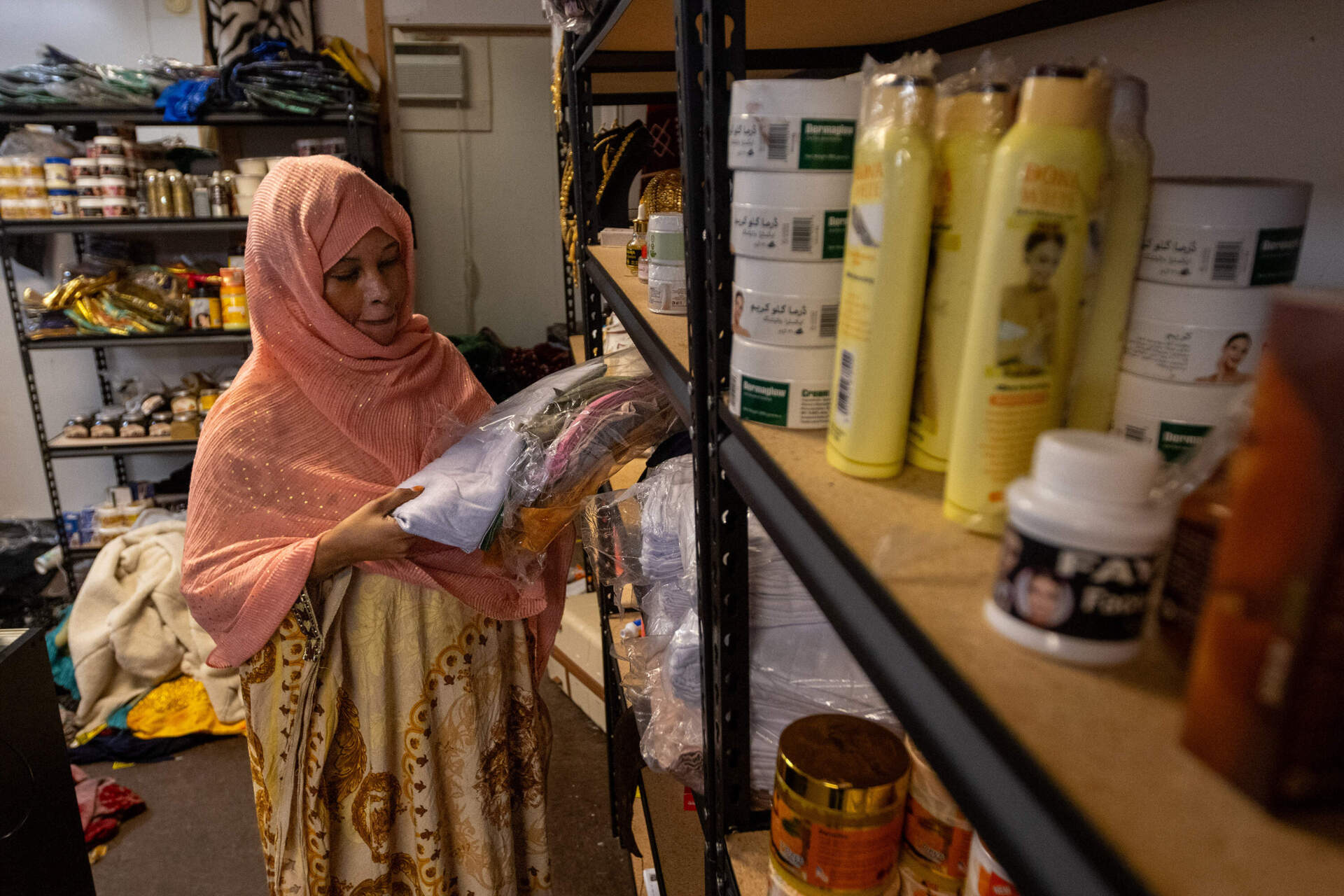 Fayere Hussein restocks the shelves at her store Ali Halal Market. She said she's noticed a significant downturn in business due to fear of the ICE surge in Lewiston. (Jesse Costa/WBUR)