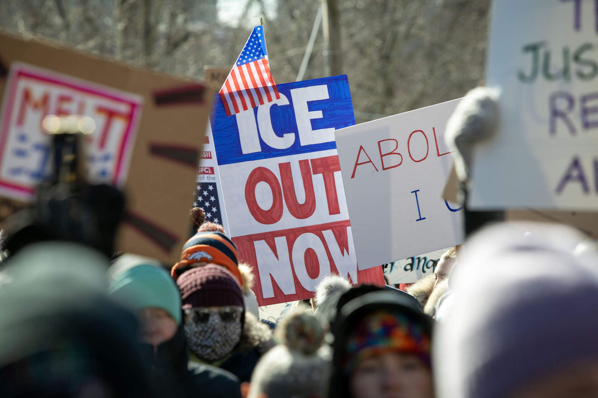 A protester holds a sign saying "ICE Out Now" at the "ICE Out Everywhere" rally at the State House in Boston. (Robin Lubbock/WBUR)