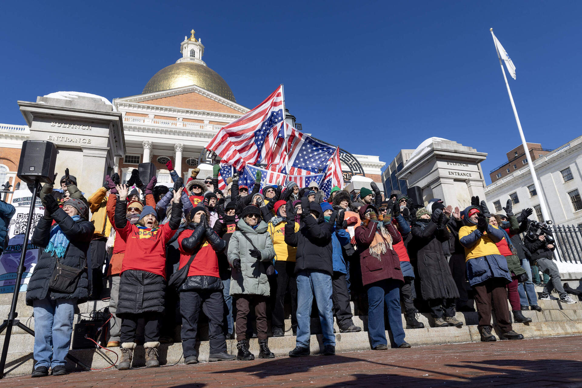 A community singing group called "B Vocal" sings a protest song for demonstrators at the "ICE Out Everywhere" rally at the State House in Boston. (Robin Lubbock/WBUR)