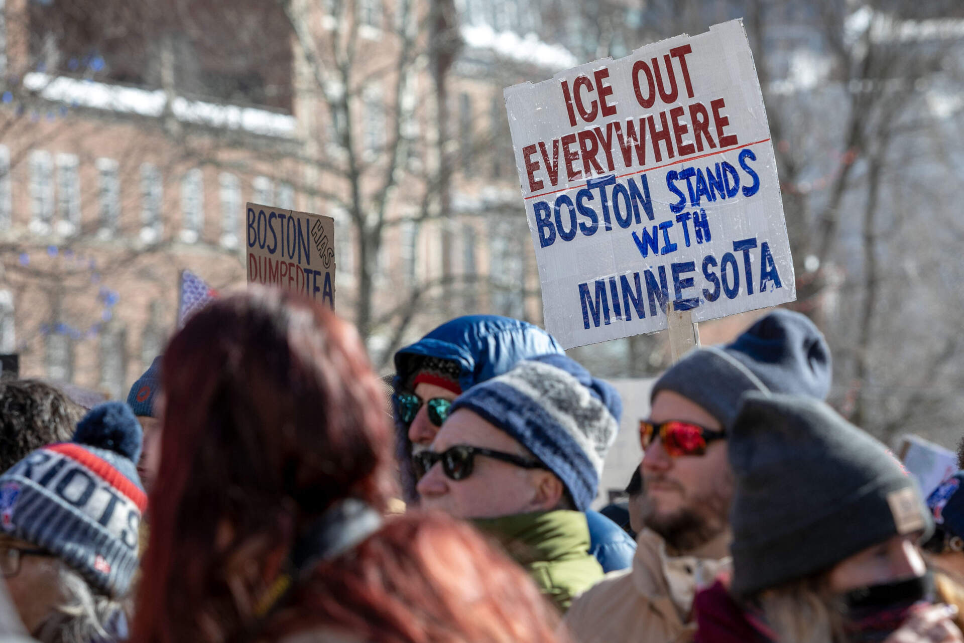 A protester holds a sign saying "ICE Out Everywhere - Boston stands with Minnesota" at the ICE Out Everywhere rally at the State House in Boston. (Robin Lubbock/WBUR)