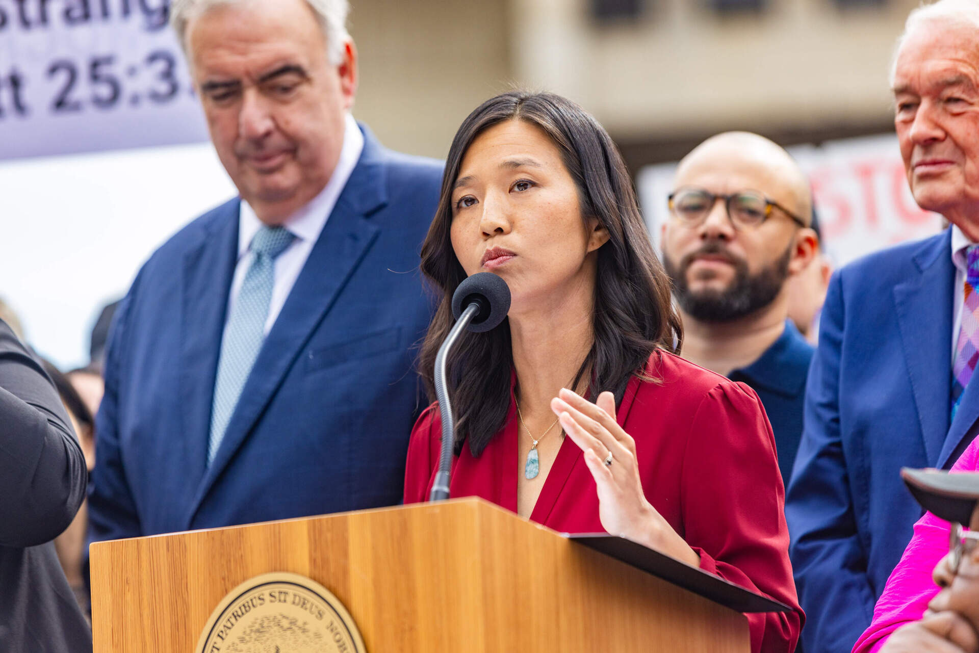 Mayor Michelle Wu, joined by community members and elected officials, criticizes the Department of Justice during a press conference at City Hall Plaza last August. (Jesse Costa/WBUR)