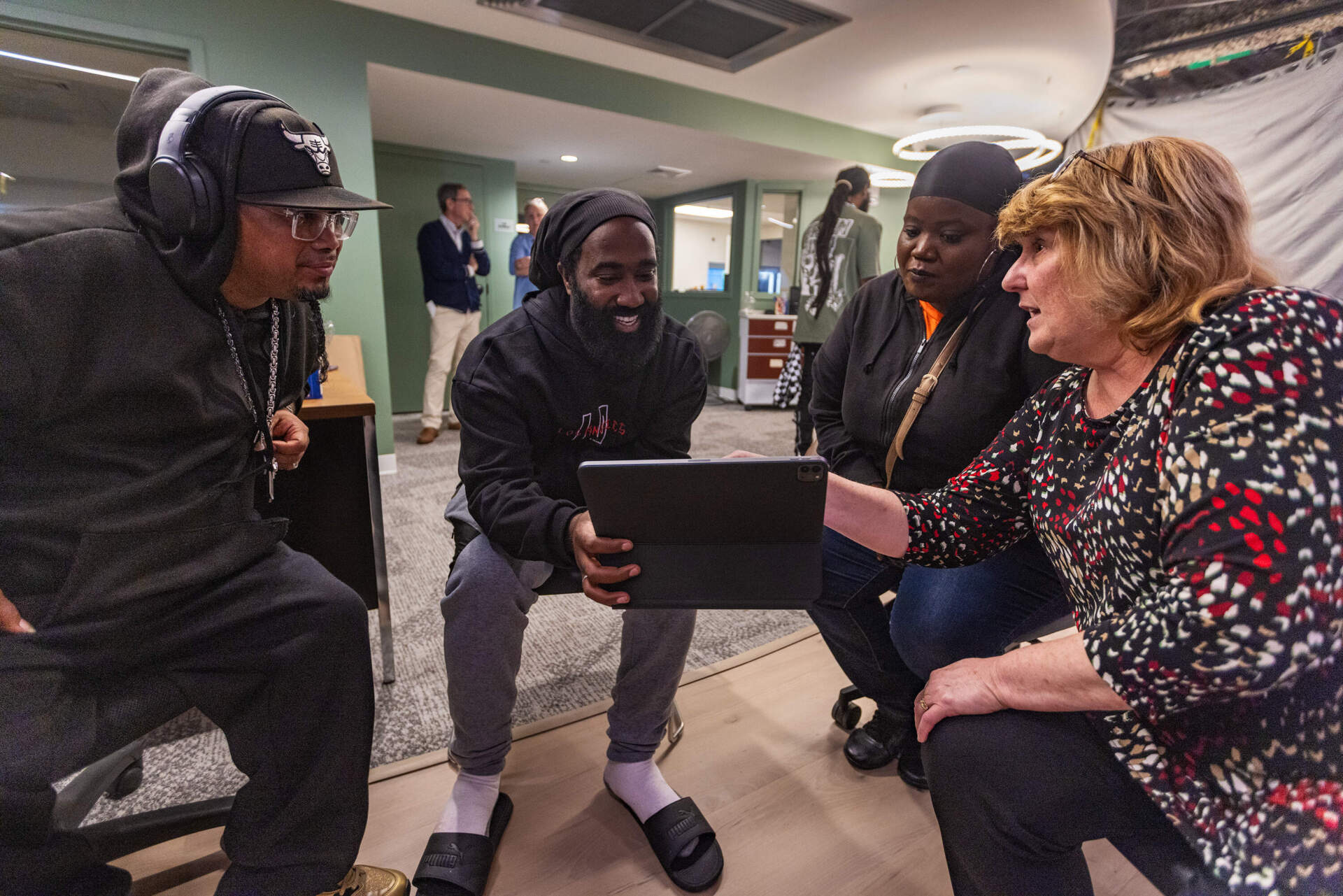 Henry Blocker, Jeffrey Eduardo and Murielle Cadet, all of whom have gotten help at St. Francis House, look at design renderings with President &amp; CEO Karen LaFrazia. (Jesse Costa/WBUR)