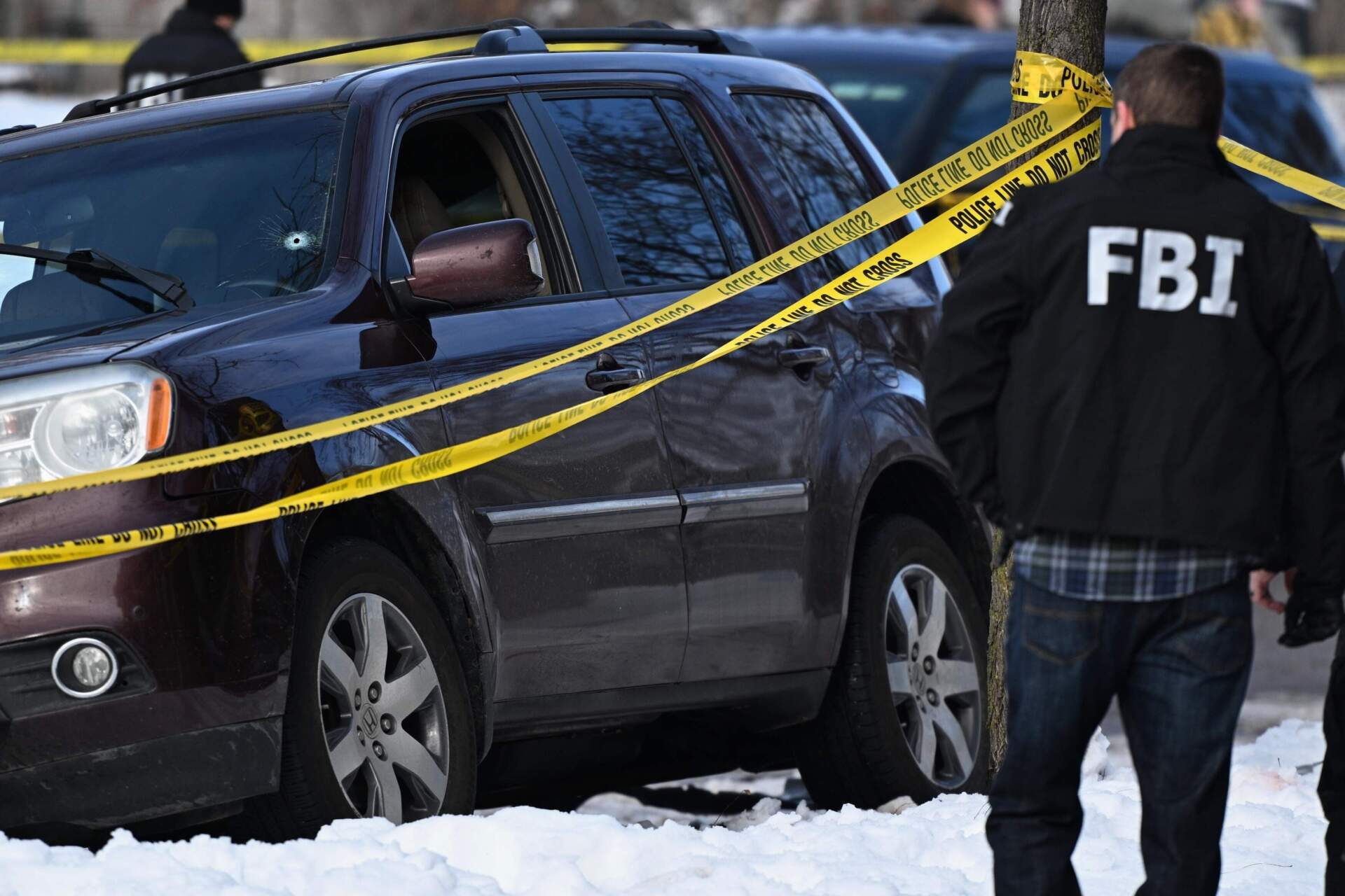 A bullet hole is seen in the windshield as federal law enforcement officers attend to the scene after an ICE agent shot a woman in her vehicle on Jan. 7 in Minneapolis. (Tom Baker/AP)