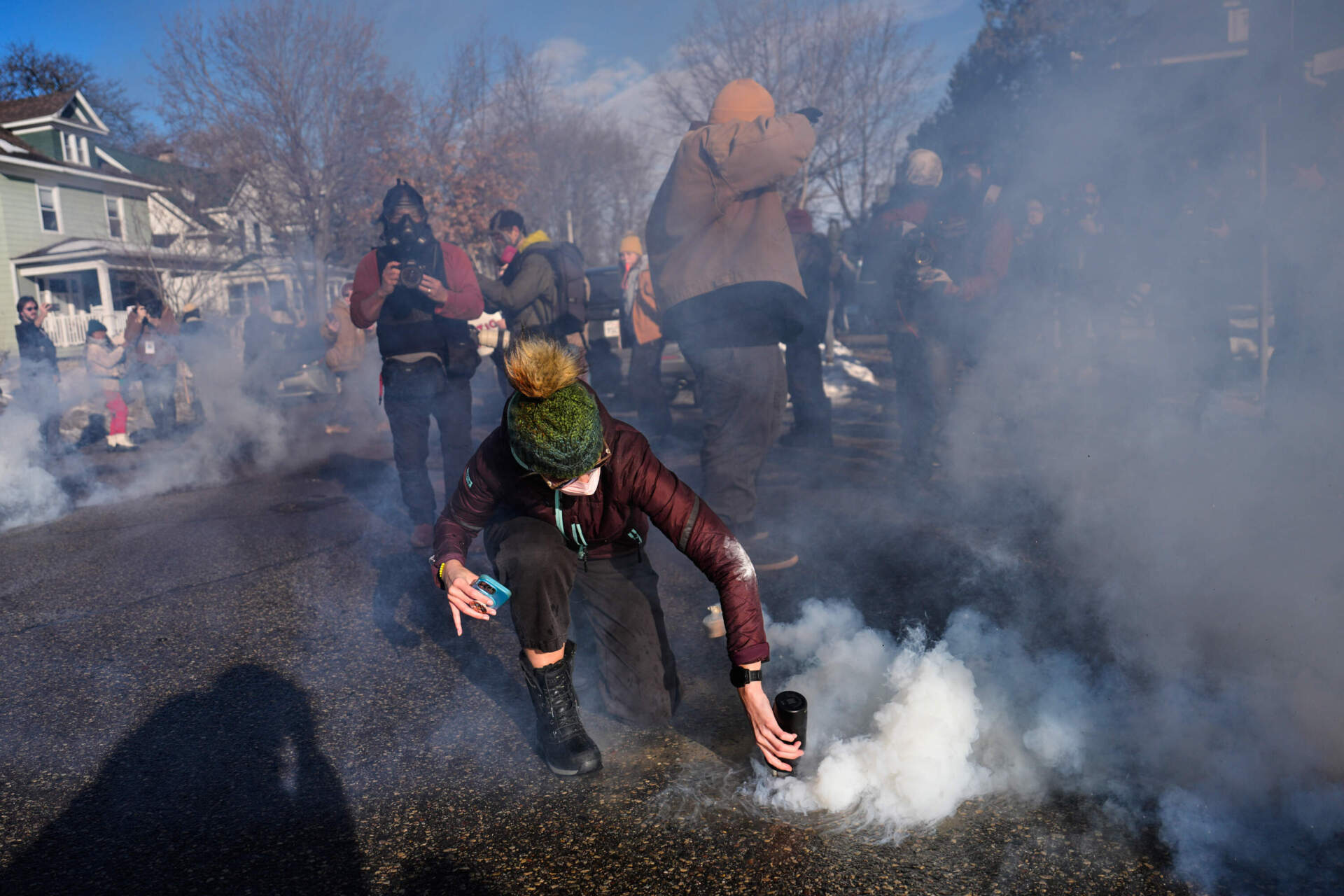 A protester covers a tear gas canister deployed by federal immigration officers on Jan. 13 in an area near where Renee Macklin Good was fatally shot by an ICE officer last week in Minneapolis. (John Locher/AP)