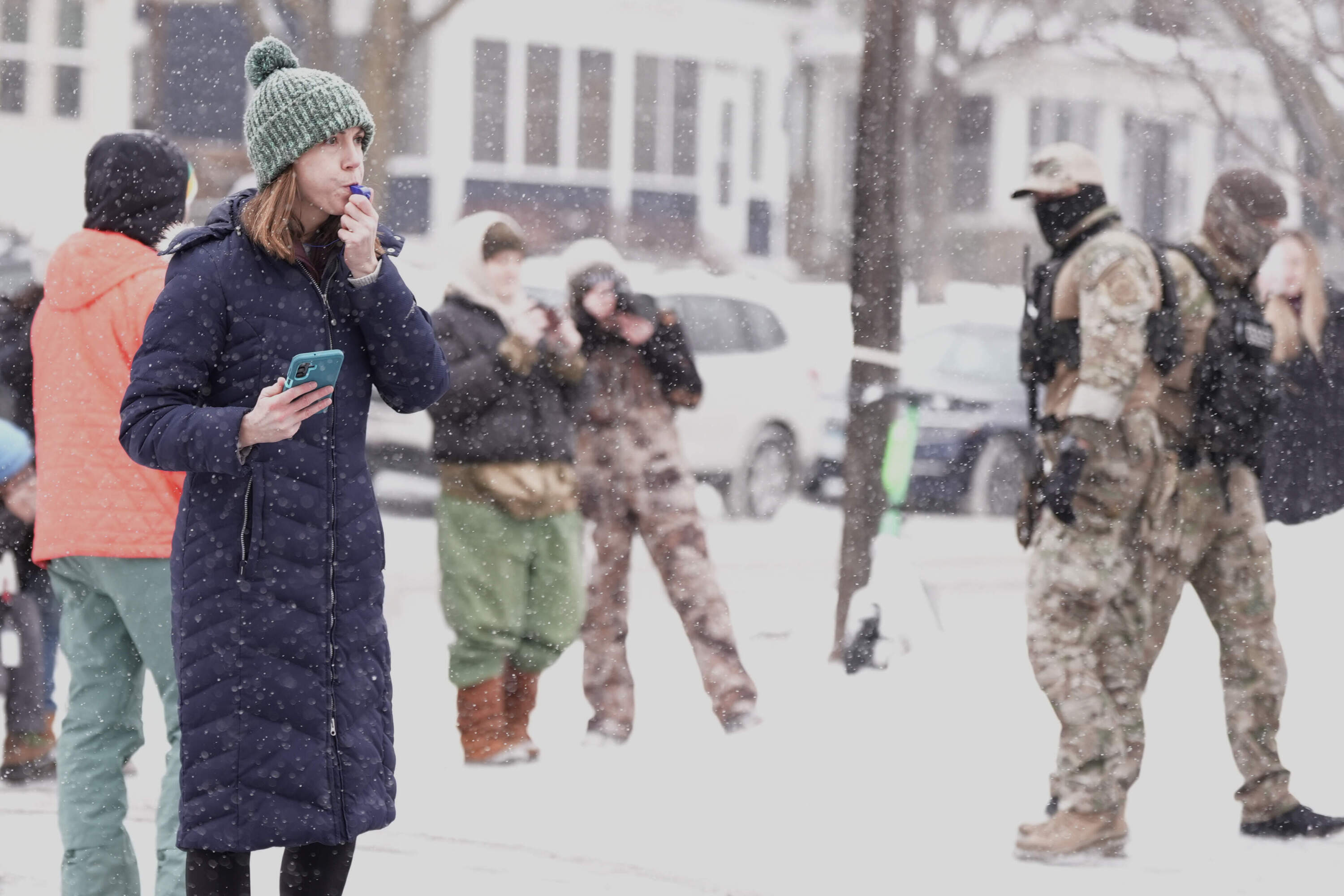 Observers look on as federal agents stand outside a convenience store on Wednesday, Jan. 21, 2026, in Minneapolis. (Angelina Katsanis/AP)