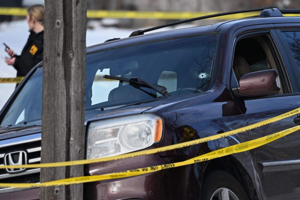 A bullet hole is seen in the windshield as federal law enforcement officers attend to the scene after an ICE agent shot a woman in her vehicle on Jan. 7 in Minneapolis. (Tom Baker/AP)
