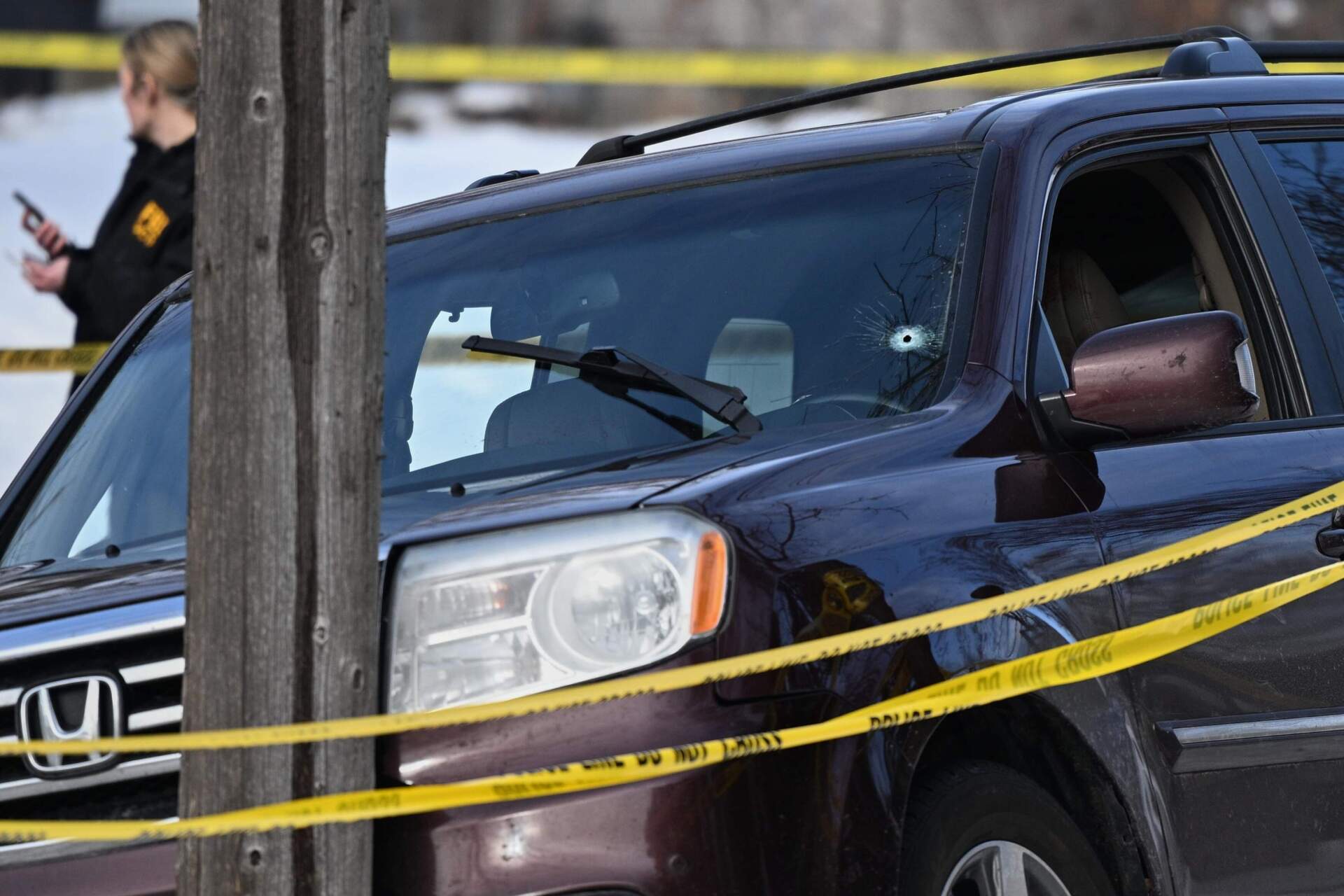 A bullet hole is seen in the windshield as federal law enforcement officers attend to the scene after an ICE agent shot a woman in her vehicle on Jan. 7 in Minneapolis. (Tom Baker/AP)