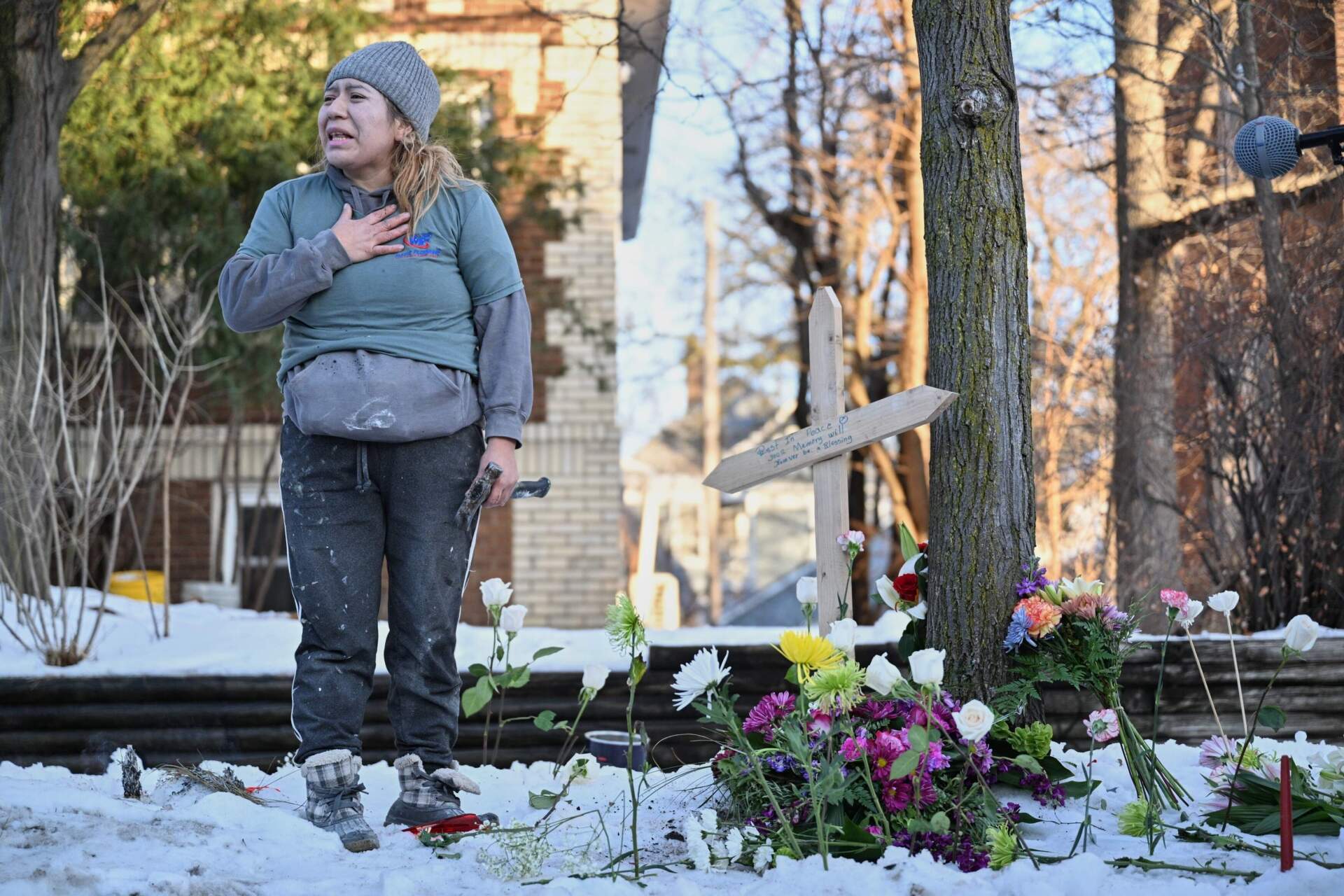 A protester stands next to a makeshift memorial honoring the woman who an ICE agent shot on Wednesday, Jan. 7. (Tom Baker/AP)