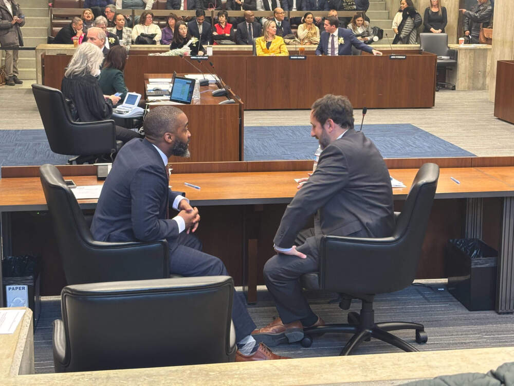 Boston city councilors Brian Worrell and Ben Weber discuss a pending vote for council president during a recess in Monday's meeting (Eve Zukoff/WBUR)