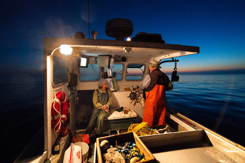 Virginia Oliver, left, talks with her son, Max Oliver, while heading out to sea to catch lobsters at dawn, Aug. 31, 2021. (Robert F. Bukaty/AP)