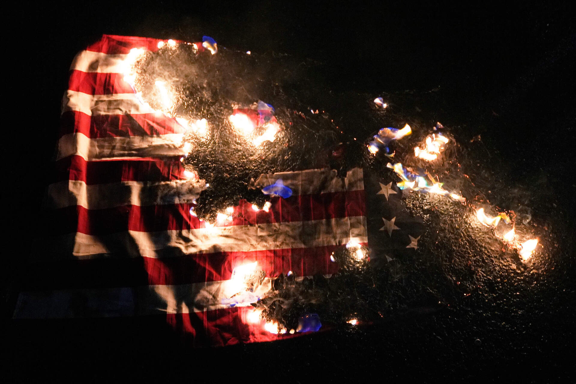 An American flag burns outside the U.S. Immigration and Customs Enforcement facility on Thursday, in Portland, Oregon. (Jenny Kane/AP)