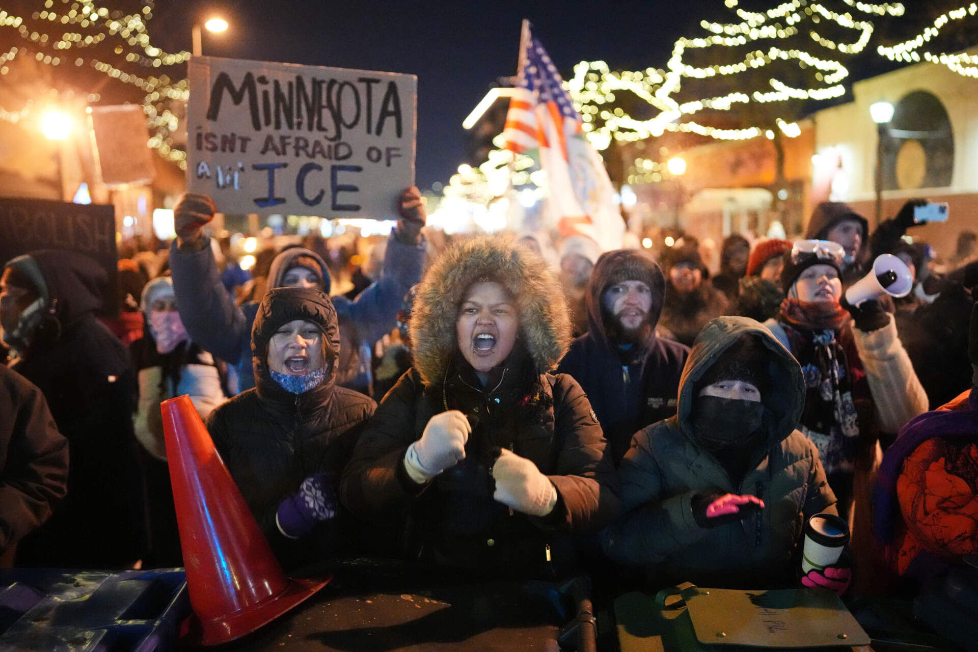 Protesters chant and bang on trash cans as they stand behind a makeshift barricade during a protest in response to the death of 37-year-old Alex Pretti, who was fatally shot by a U.S. Border Patrol officer earlier in the day, Saturday, Jan. 24 in Minneapolis. (Adam Gray/AP)