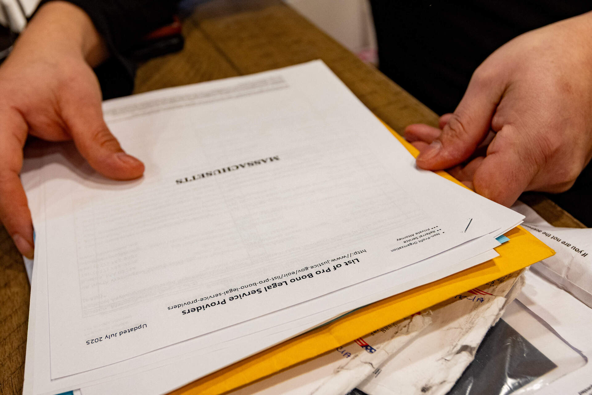 Juan pulls out a copy of pro bono legal services providers in Massachusetts from a folder of paperwork concerning his children’s immigration cases. (Jesse Costa/WBUR)