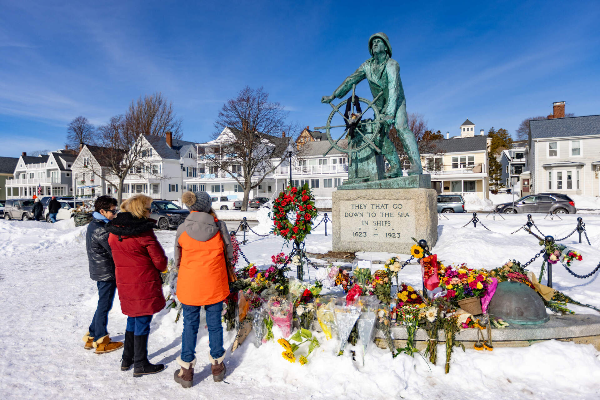 Jane Asaro Hartson, Patricia McGrath and Diana Taylor stand to honor the memory of the crew of the Lily Jean at the Fisherman’s Memorial in Gloucester on Monday. (Jesse Costa/WBUR)