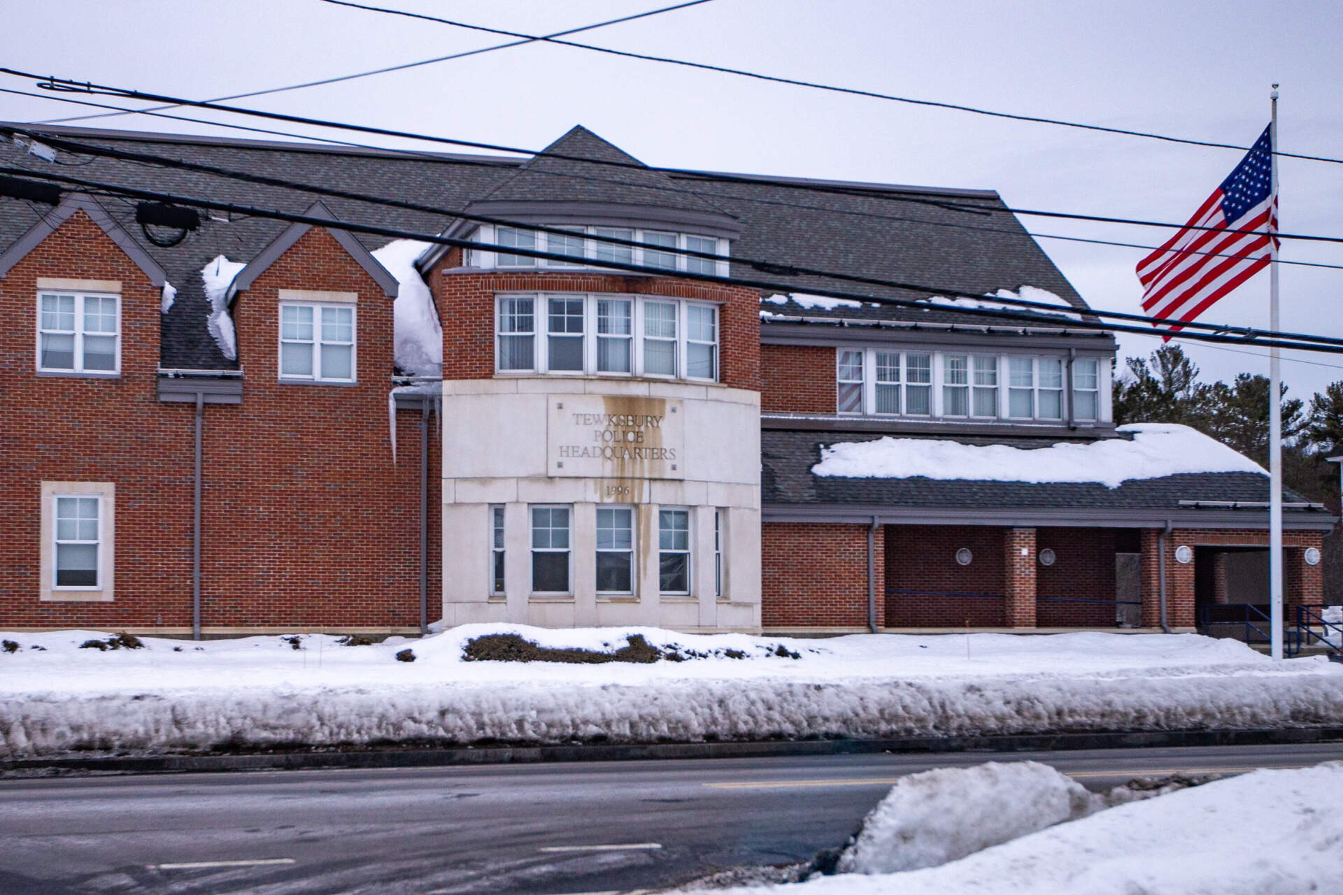 A flag blows in the wind outside Tewksbury Police Headquarters. (Jesse Costa/WBUR)