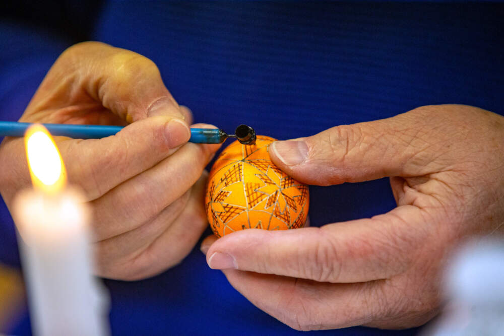 Anna Nosal applies wax onto an egg with a kistka to mask out any additional dye she will use. (Jesse Costa/WBUR)