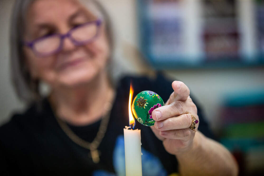 Stephanie Majkut melts the wax off of the egg she designed with a candle. (Jesse Costa/WBUR)