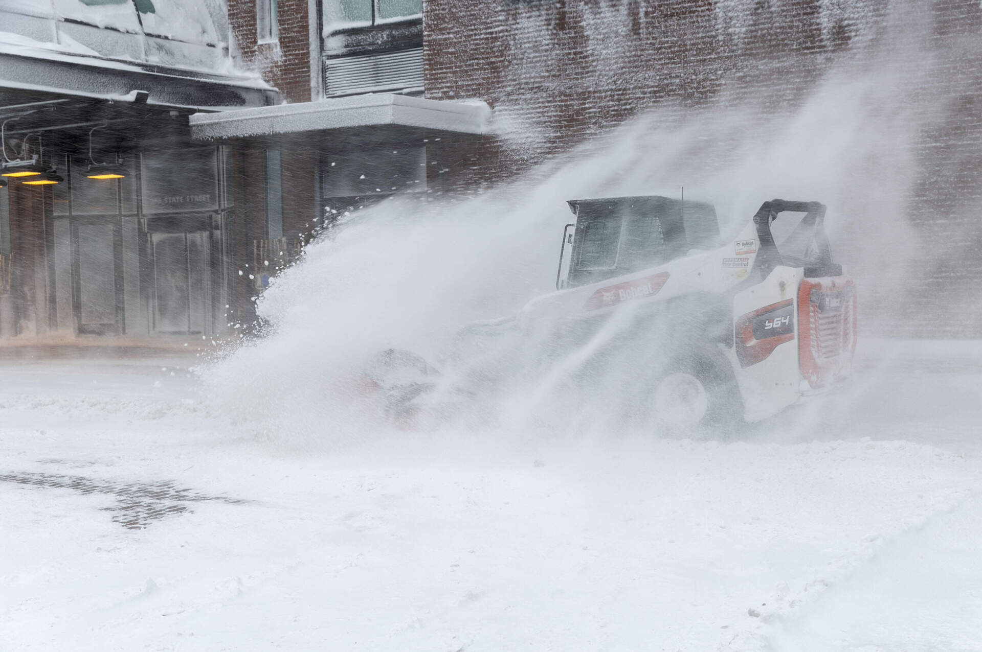 A Bobcat sweeps snow during the storm Monday on Long Wharf. (Robin Lubbock/WBUR)