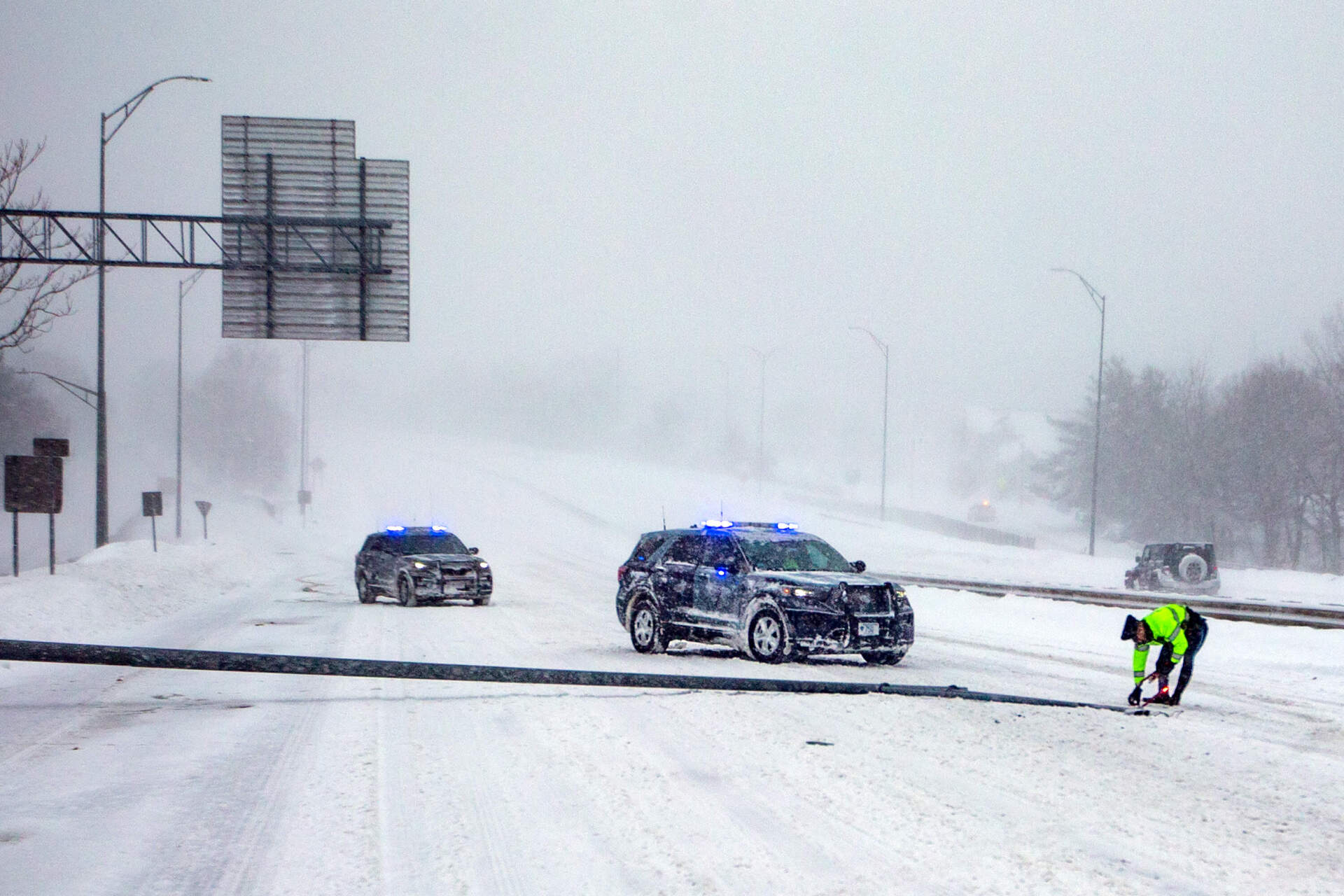 A Massachusetts State Police officer lays down flares to mark a light post straddling two lanes blown down by the winds of the nor’easter on Route 2 in Belmont. (Jesse Costa/WBUR)