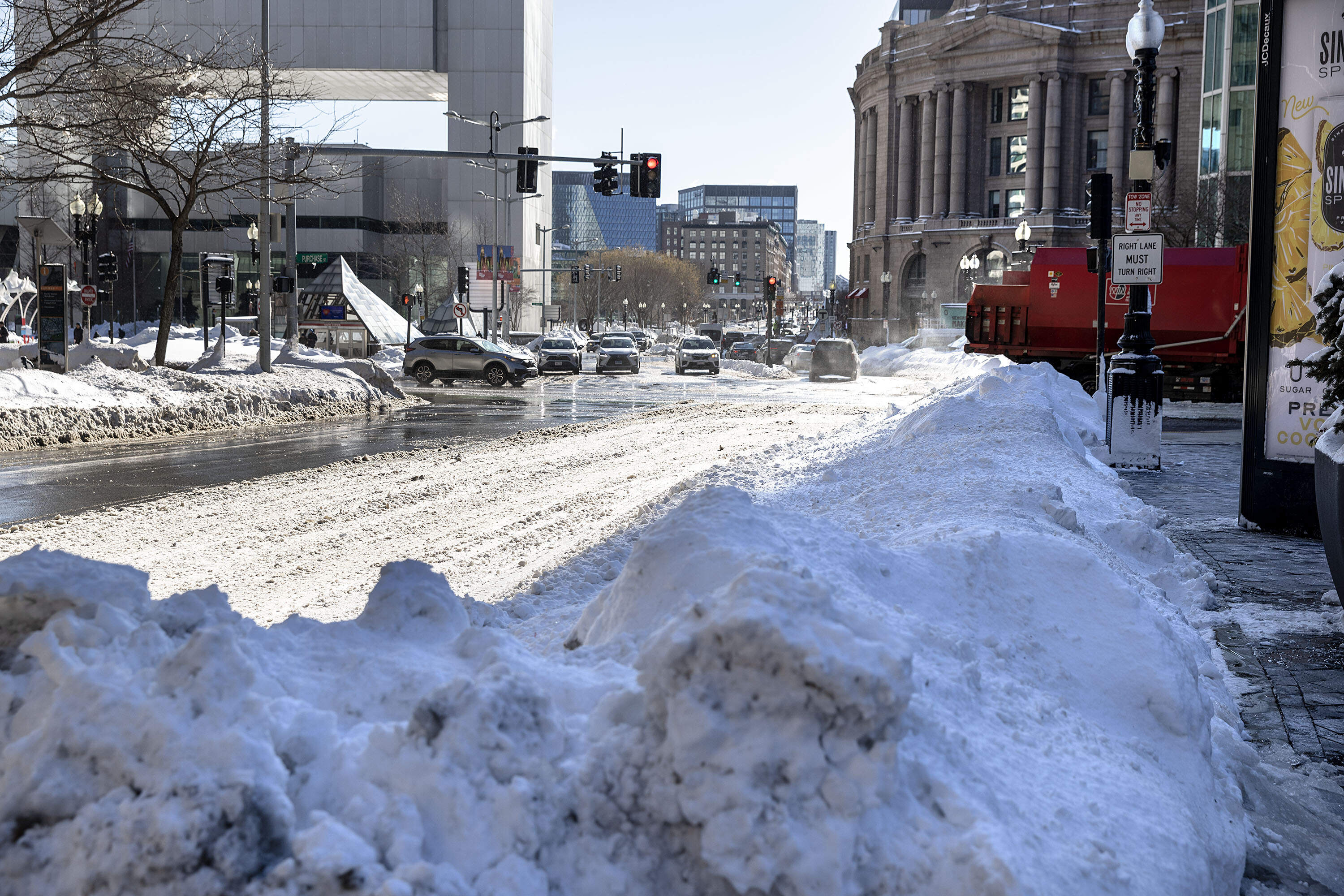 Vehicles drive along a snowy Summer Street by Boston's South Station as cleanup gets underway Tuesday after the nor'easter.