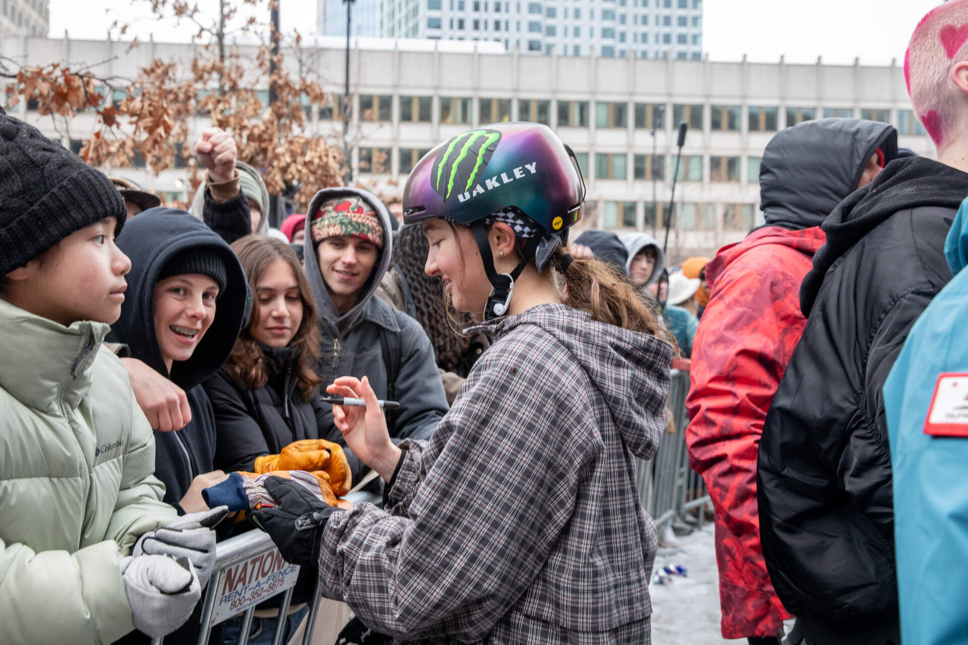 Jessica Perlmutter, 2026 U.S. Olympian and reigning Red Bull Heavy Metals winner, signs the gloves of Charlie Thomas of Wellesley. Thomas was most excited to see Perlmutter and snowboarder Zeb Powell. (Artemisia Luk/WBUR)
