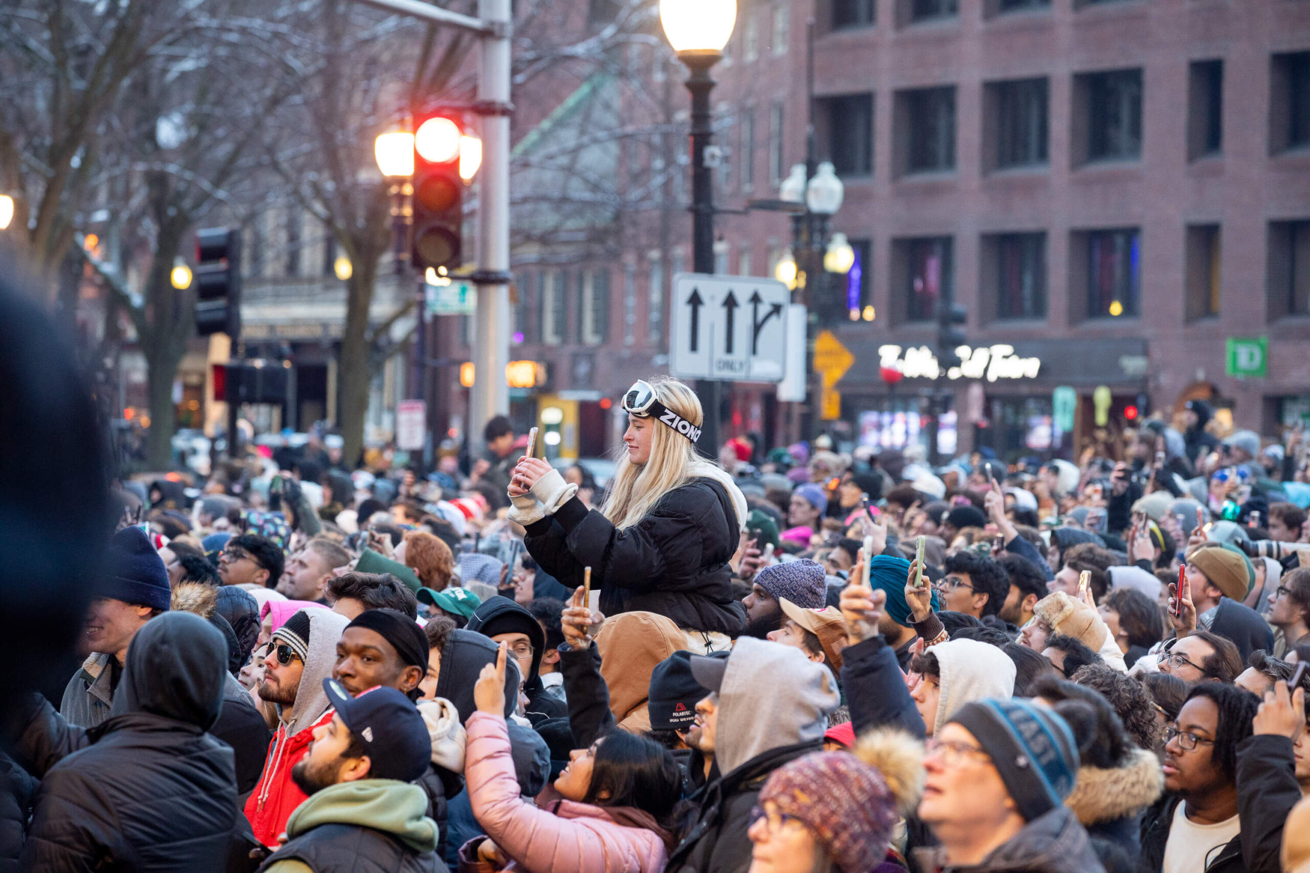 A spectator wearing ski googles snaps a picture of the snowboarding competition. (Artemisia Luk/WBUR)
