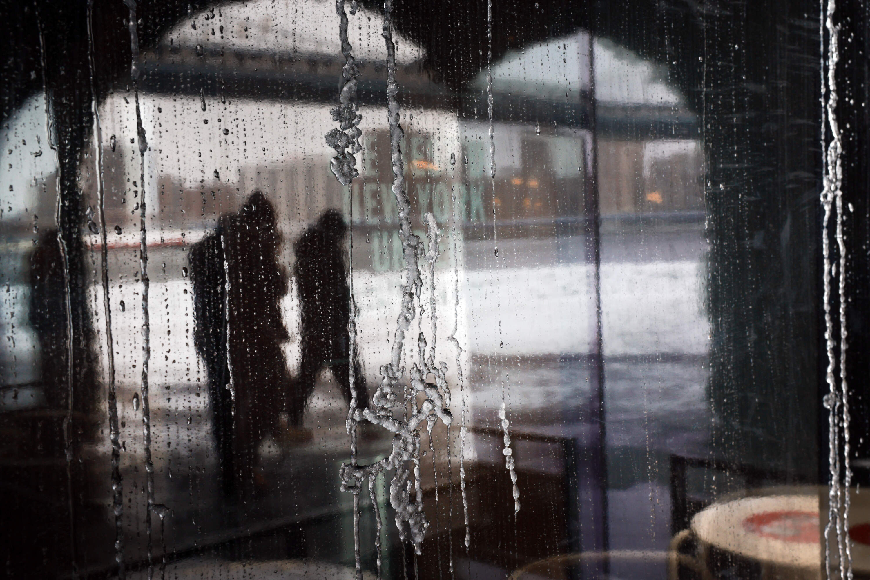 People are reflected in an ice-covered door in Brooklyn after an overnight storm on December 27, 2025, in New York City. (Spencer Platt/Getty Images)