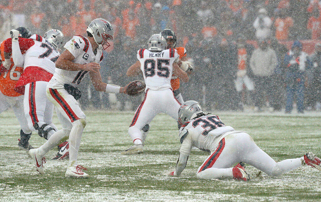 New England Patriots running back Rhamondre Stevenson slips before quarterback Drake Maye can hand him the ball in the fourth quarter in the AFC Championship Game at Empower Field at Mile High on January 25, 2026. (Barry Chin/The Boston Globe via Getty Images)