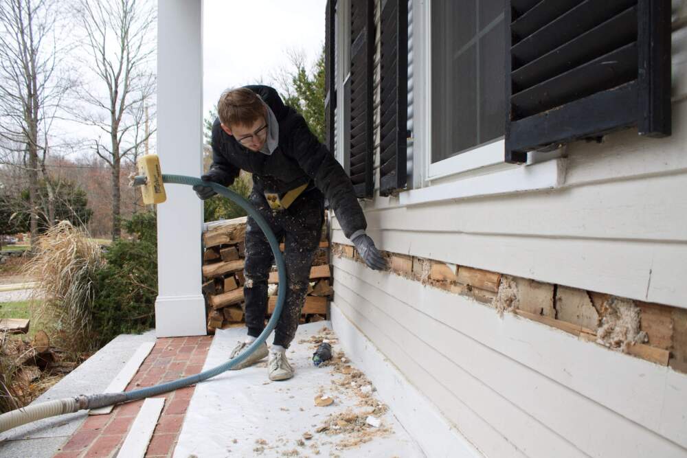 Insulation is blown into the walls of a home in Massachusetts. (Miriam Wasser/WBUR)
