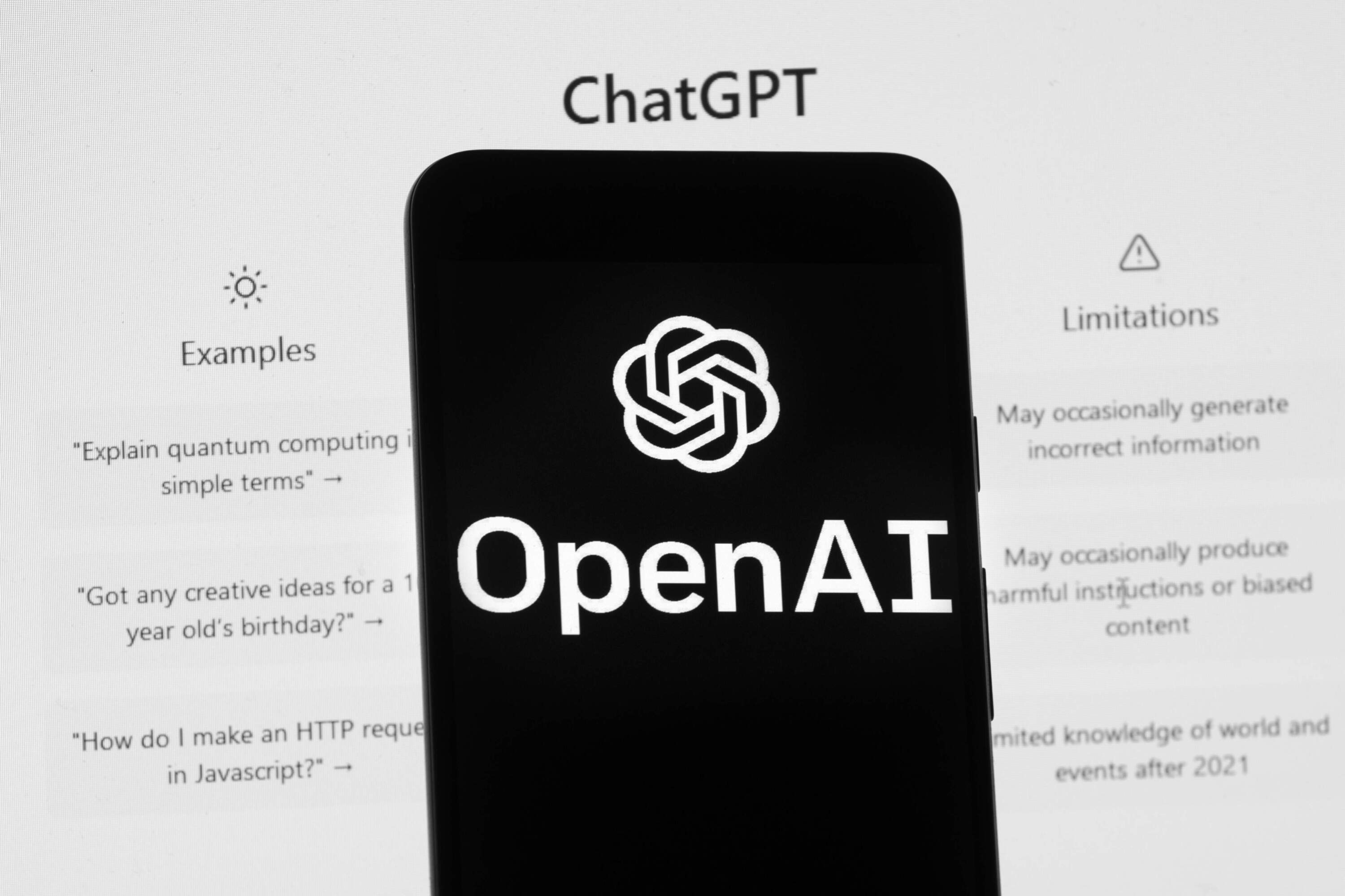 The OpenAI logo is seen on a mobile phone in front of a computer screen which displays the ChatGPT home Screen, on March 17, 2023, in Boston. (Michael Dwyer/AP)