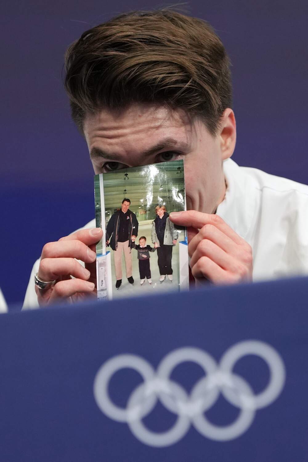Naumov waits for his scores while holding a photo of his parents. (Francisco Seco/AP)