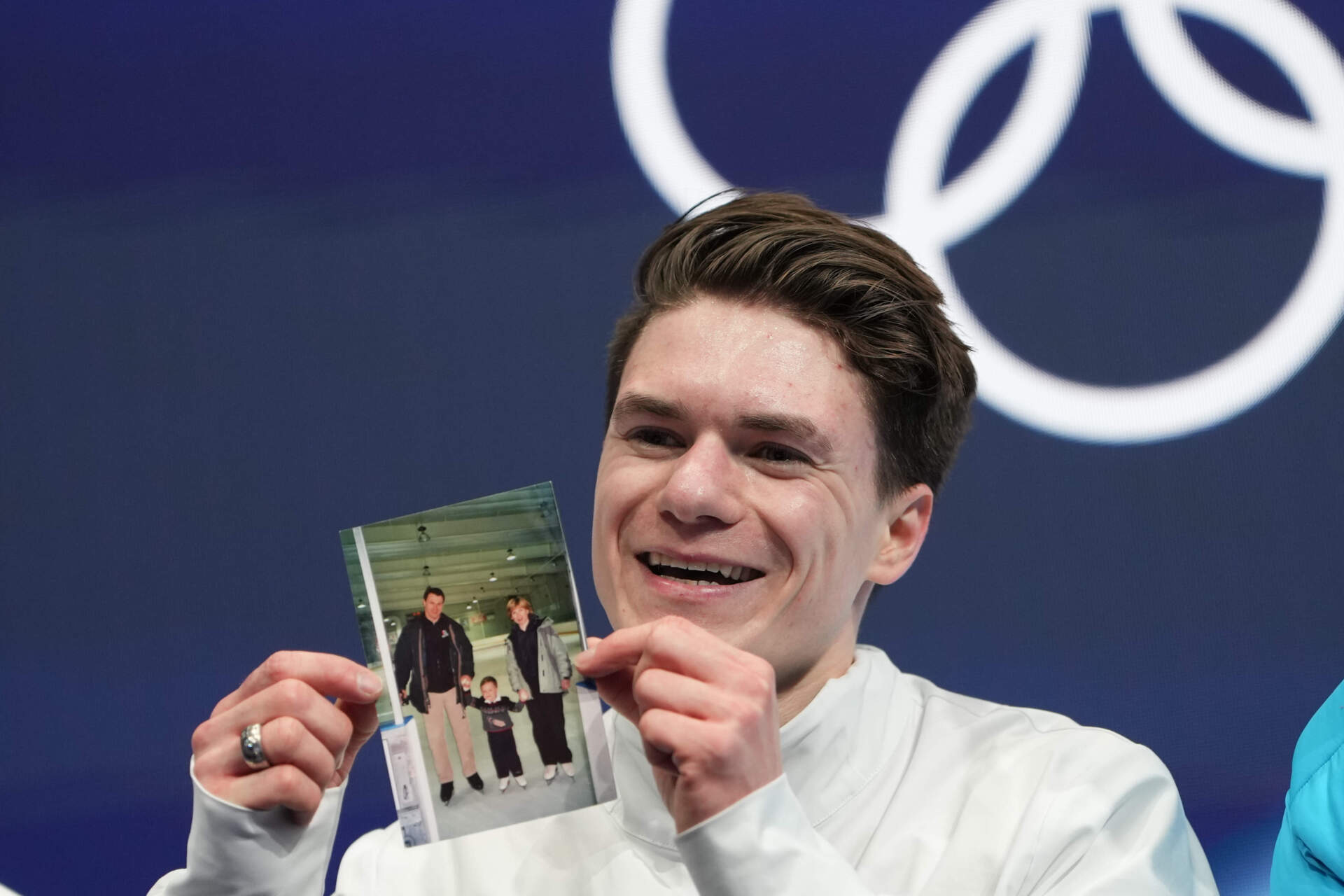 Team USA's Maxim Naumov waits for his scores during the men's figure skating short program Tuesday while holding a photo of his parents, who died in a 2025 plane crash in Washington, D.C. (Francisco Seco/AP)