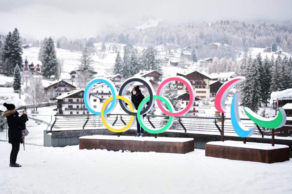 People take photos in front of the Milan Cortina Winter Olympics and Paralympics rings, in Cortina D'Ampezzo. (Andrew Medichini/AP file)