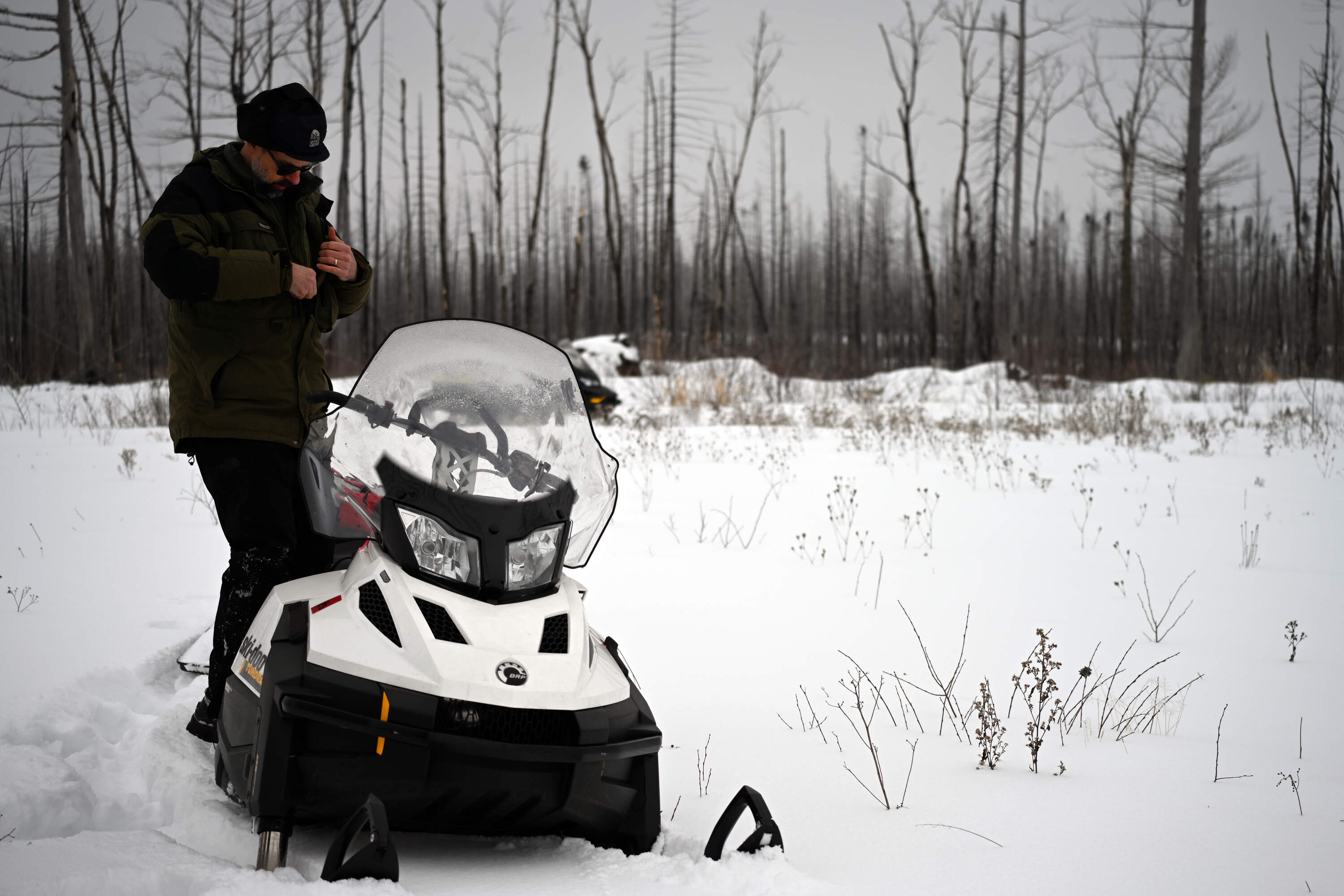 From his snowmobile, Chris Dunham looks for evidence that efforts to rebuild moose habitats are working. (Chris Bentley/Here &amp; Now)