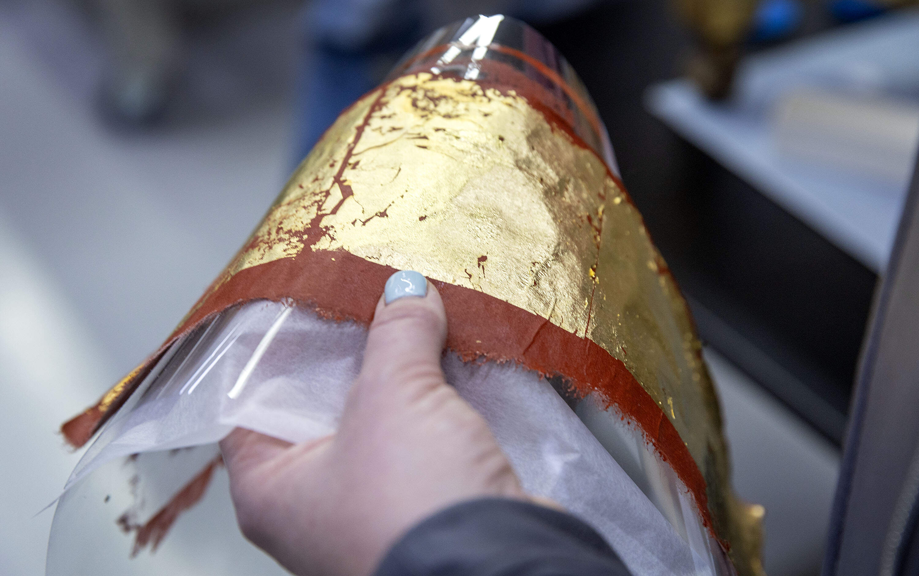 Salmon holds a sheet of gold leaf for the restoration of the chairs from the Gardner Museum's Dutch Room. (Robin Lubbock/WBUR)