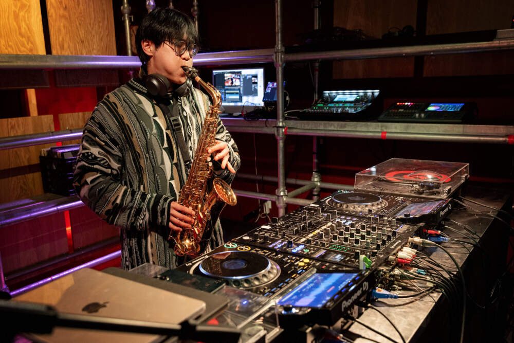 Saxophonist Andrew Wei, also known as DJ ILUV8, works on his set at the Central on Air studio in Cambridge, Mass. (Robin Lubbock/WBUR)
