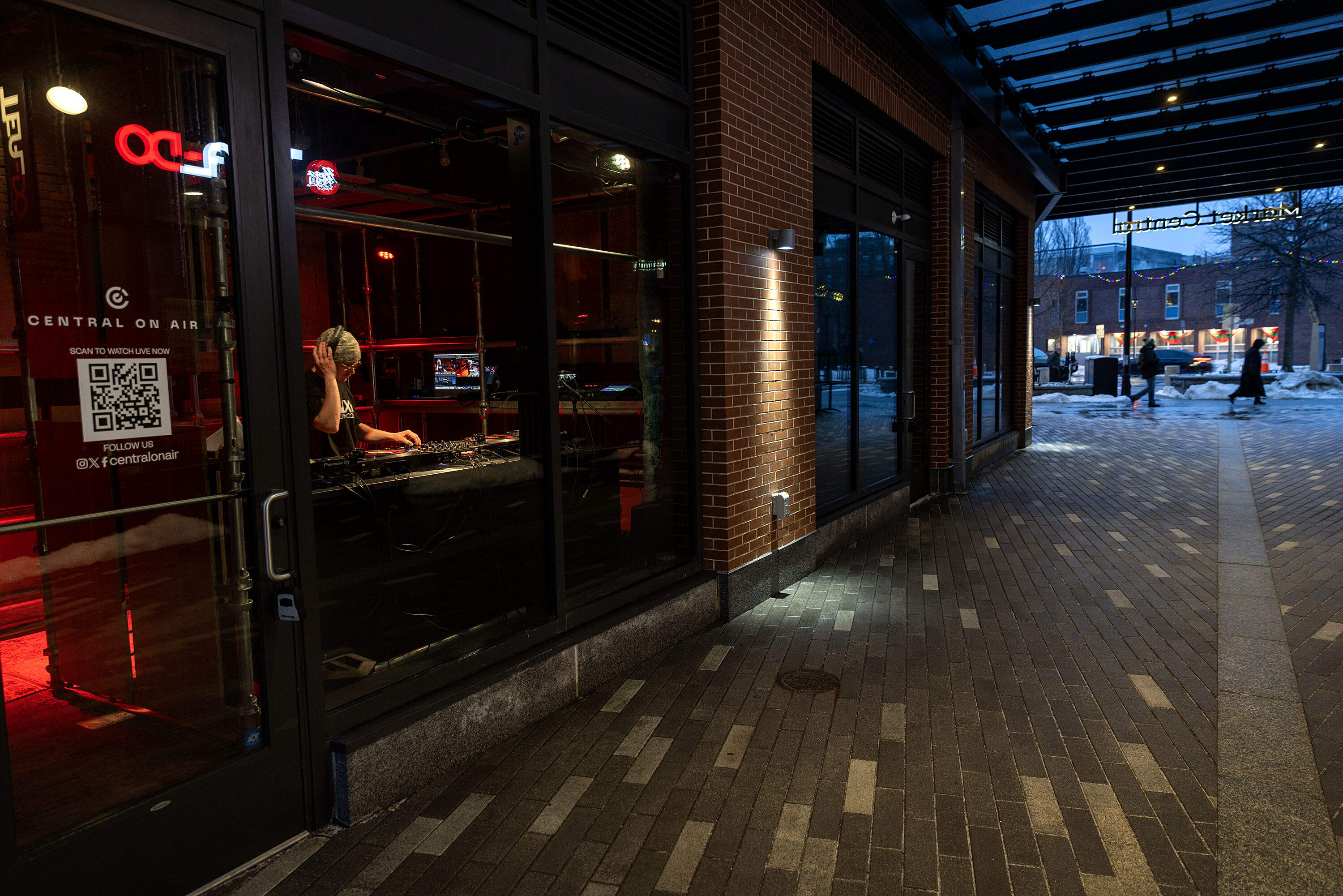 People walk along Massachusetts Ave. as DJ Mars Jptr streams from the studio of Central on Air in Cambridge, Mass. (Robin Lubbock/WBUR)