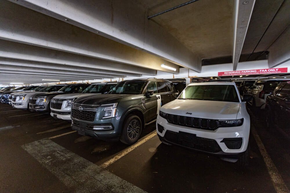 A row of brand new SUVs parked in the garage behind 800 District Avenue in Burlington with spots that say they're reserved for FAA vehicles. (Jesse Costa/WBUR)