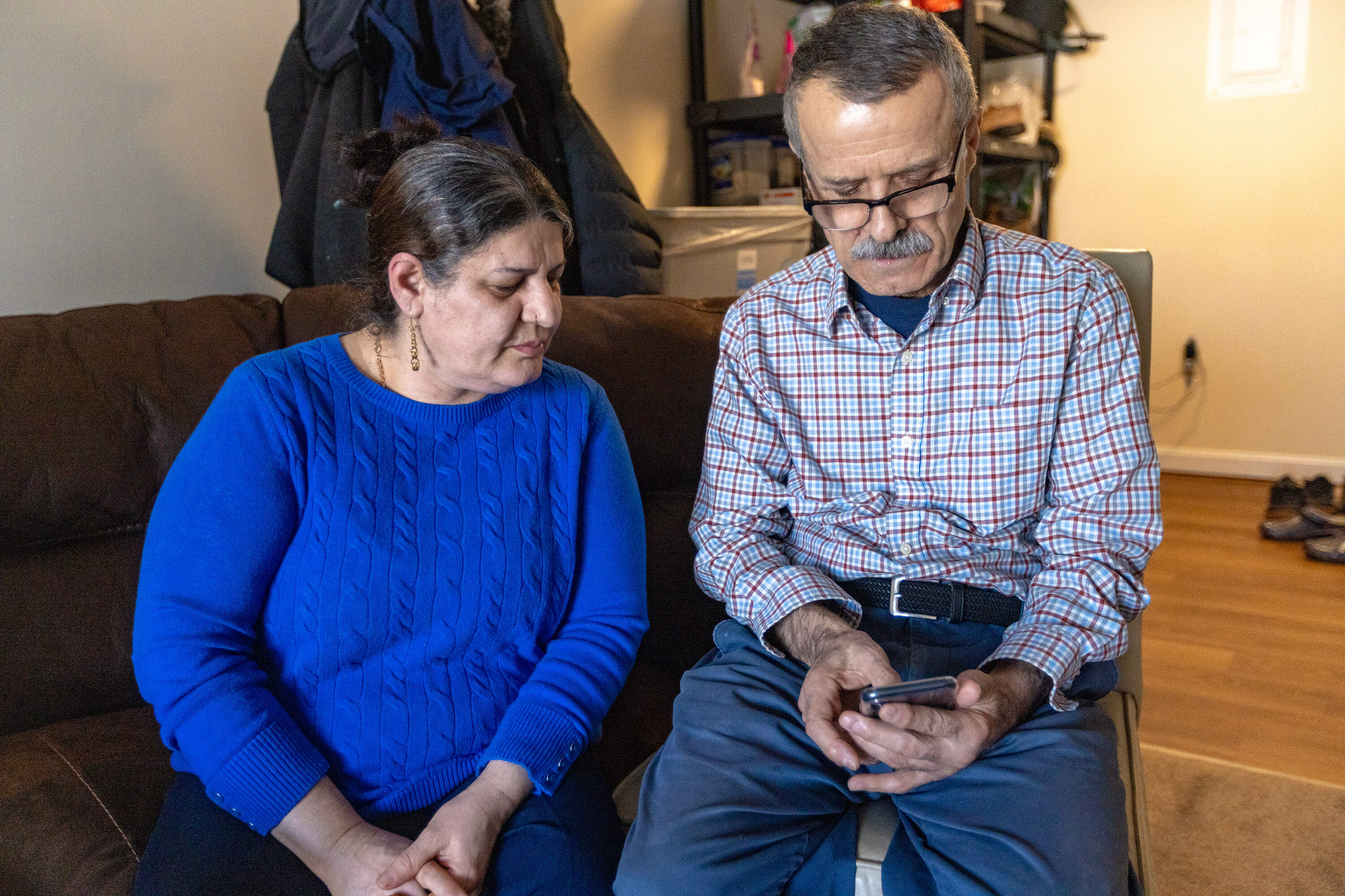 Sorayya and Karim Haddadi look at the phone to see what's being posted on Facebook about the war in Iran. (Jesse Costa/WBUR)