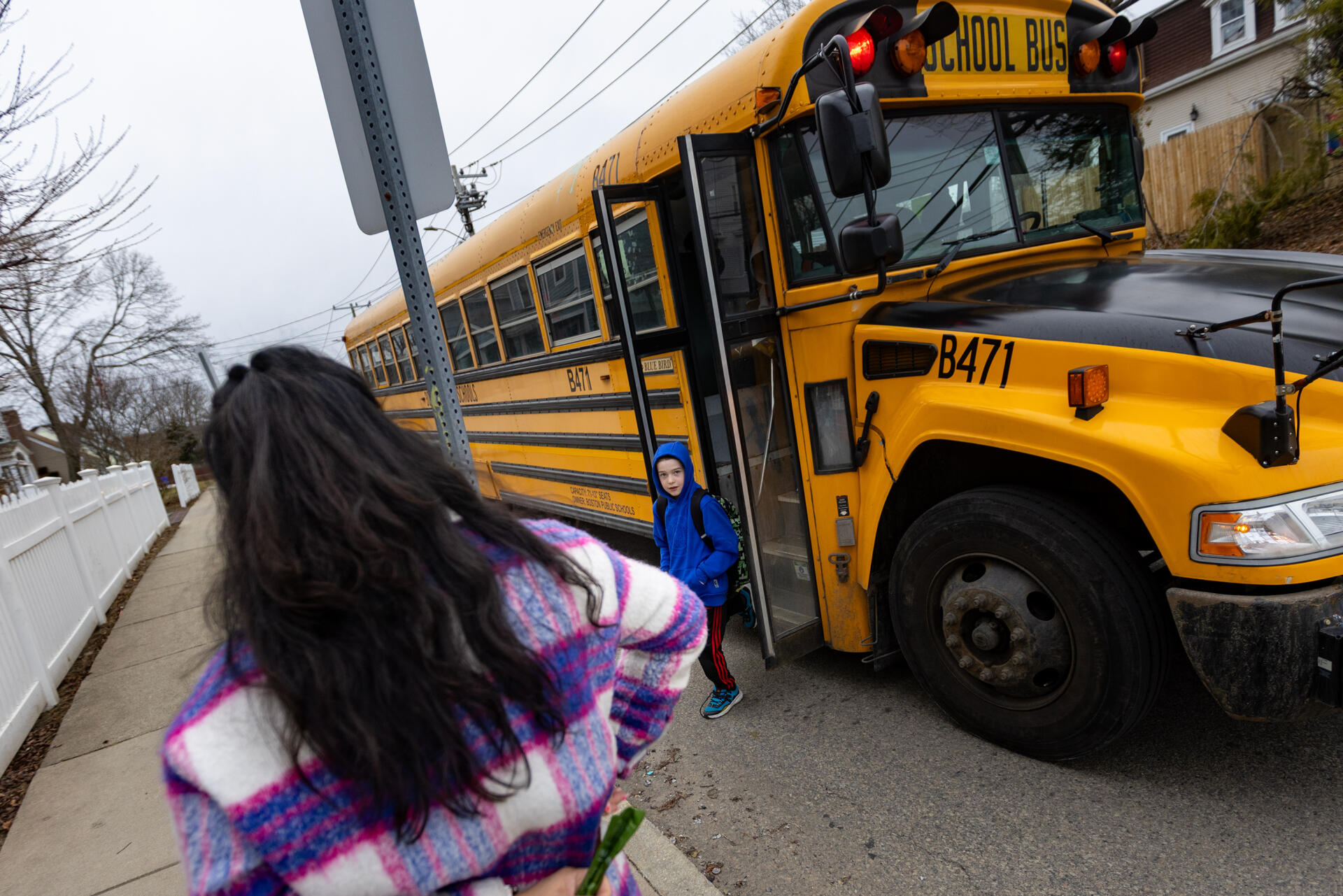 Laura Gonzales McKenna watches as her 8-year old son Asher gets off the school bus. (Jesse Costa/WBUR)