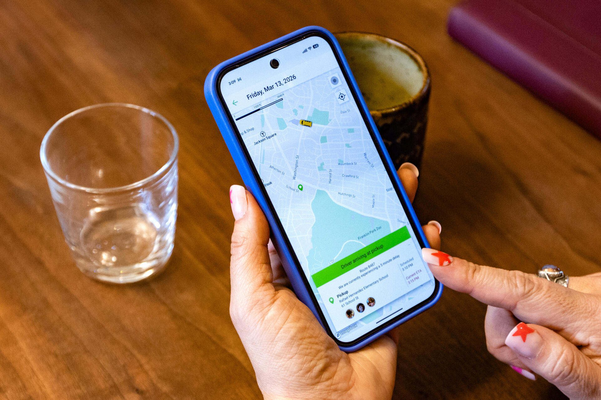 Laura Gonzales McKenna checks the bus app to see the bus hasn’t left the school yet. (Jesse Costa/WBUR)