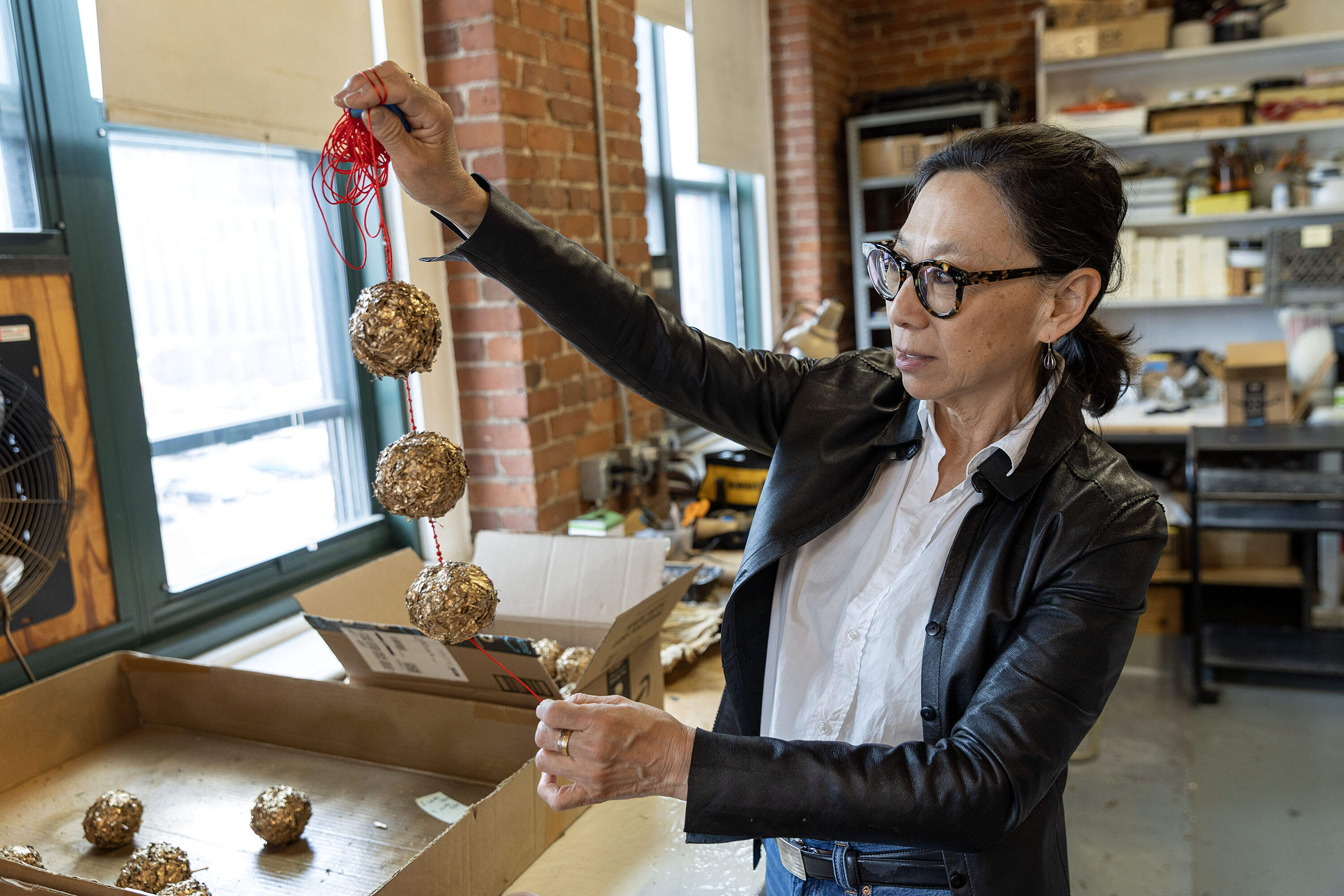Artist Yu-Wen Wu hold a string of orbs from a work in progress at her studio in Boston. (Robin Lubbock/WBUR)