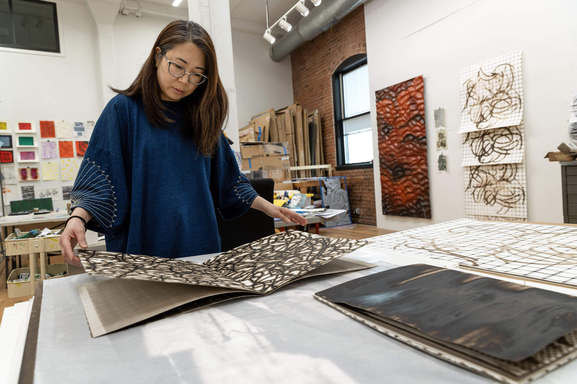 Artist Lucy Kim looks through a melanin print book at her studio in Somerville, Mass. (Robin Lubbock/WBUR)