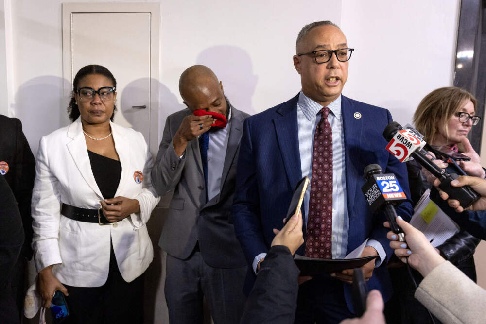 Lens Joseph's father, Esaie Joseph, wipes tears from his eyes as Suffolk County District Attorney Kevin Hayden speaks after the arraignment of former bus driver Jean Charles in Suffolk Superior Court. (Robin Lubbock/WBUR)