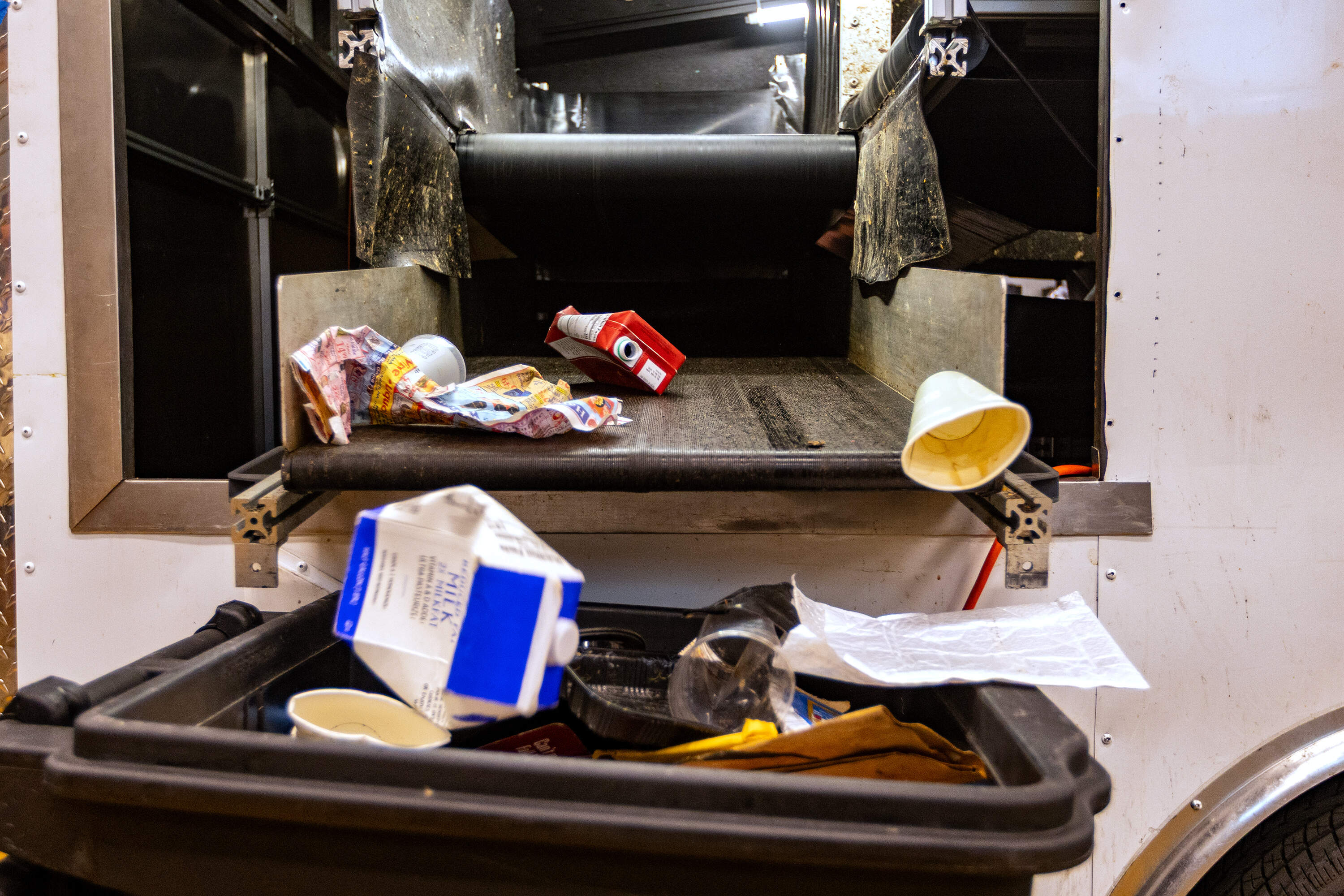 Non-recyclable materials fall into a trash from a conveyor belt can after sorting through mixed waste by the rStream Smart Sorter. (Jesse Costa/WBUR)