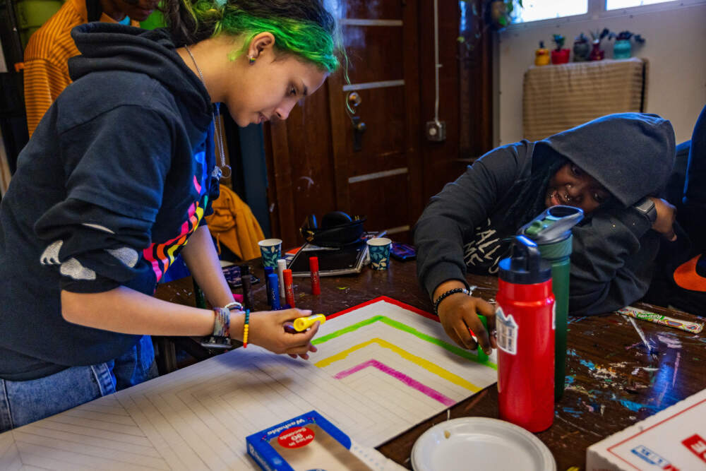 Senior Areli Lopez colors a sign and talks with classmate Quinn Holley. (Jesse Costa/WBUR)