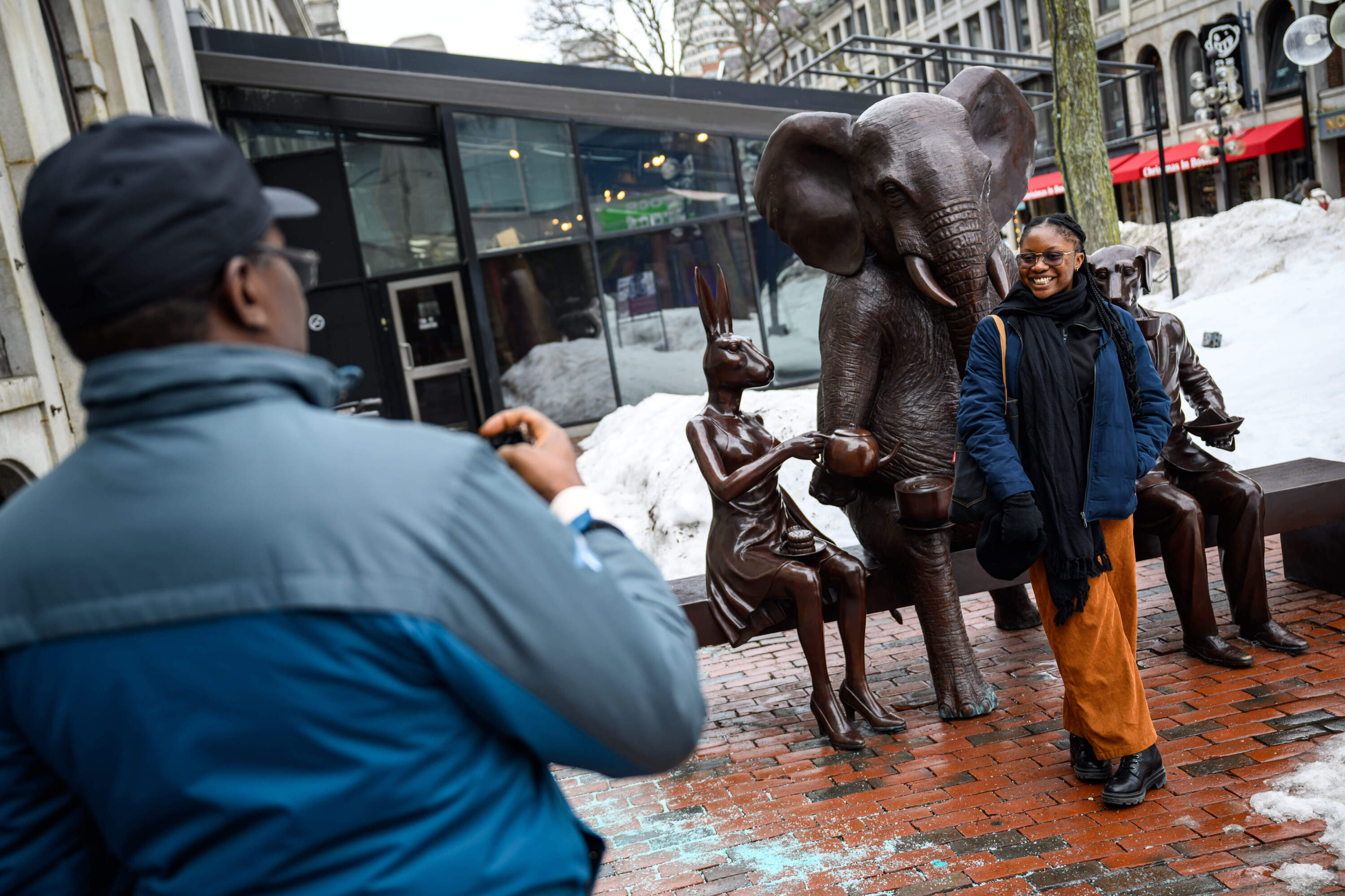 Ronald Mitti takes a picture of Sheena Mitti posing in front of The Teatime Bench on a visit to Boston. (Andrew Burke-Stevenson for WBUR)